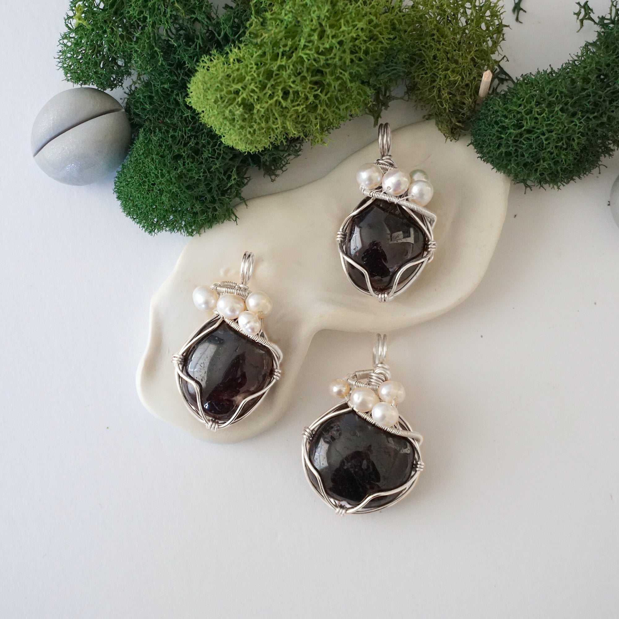 Three silver wire wrapped garnet and freshwater pearl pendants showing natural stone variation, artisan jewelry for women