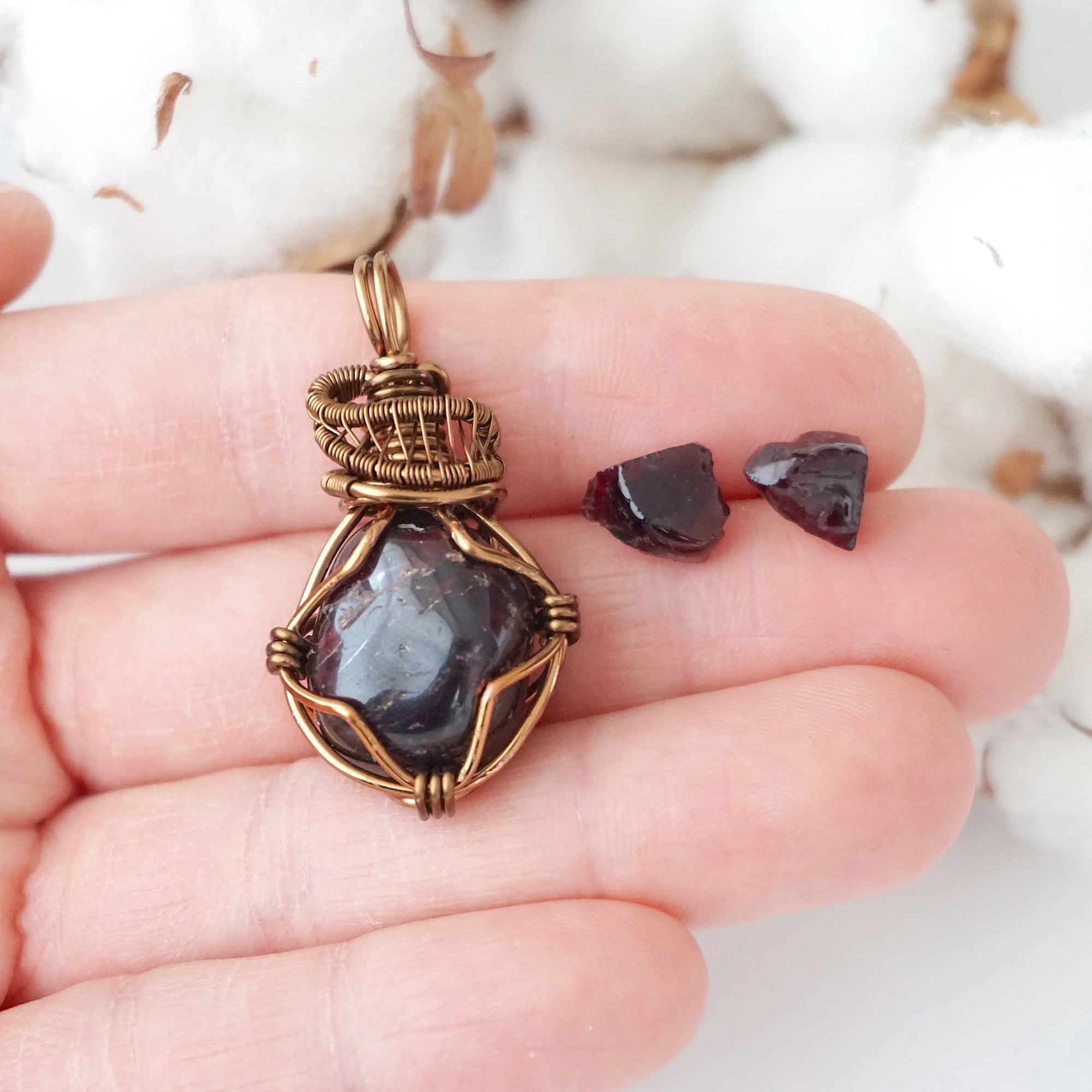 Garnet necklace pendant and stud earrings shown in hand for size reference, featuring natural garnet stones