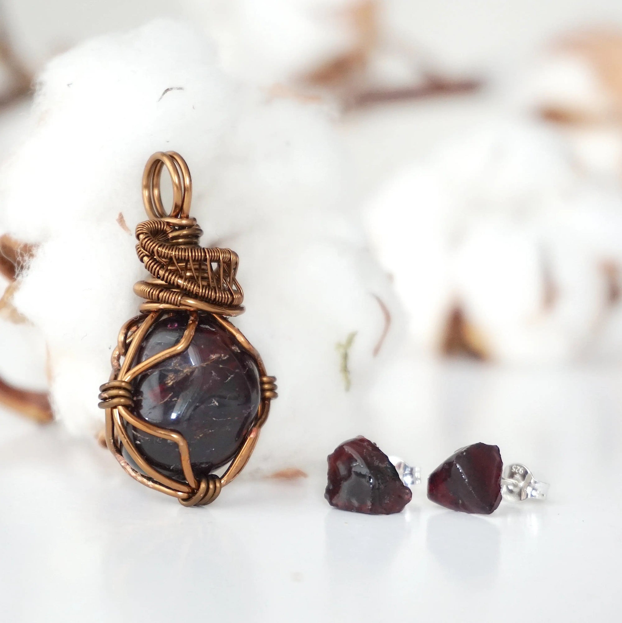 Front view of a garnet necklace and stud earrings jewelry set with an antique bronze wire wrapped pendant and sterling silver garnet studs