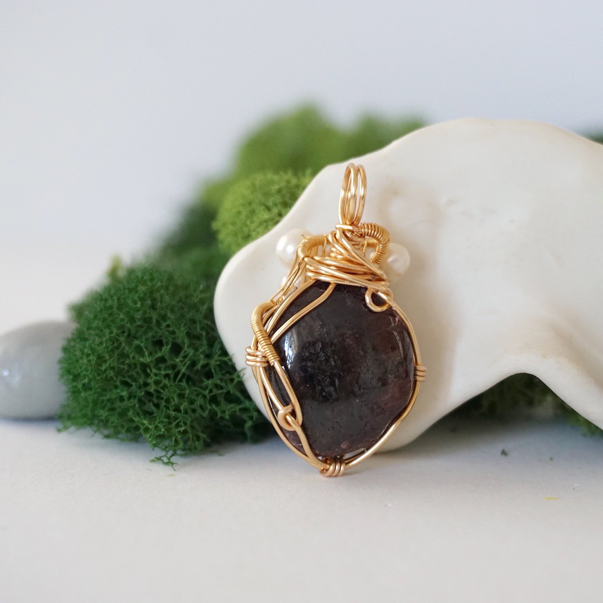 Back angle detail of garnet and freshwater pearl pendant, showing wire wrapping and natural stone