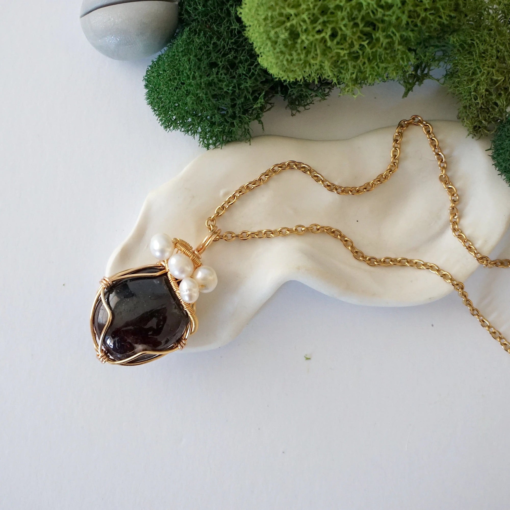 Garnet and freshwater pearl pendant on gold plated brass chain laying flat, handmade wire wrapped jewelry for women