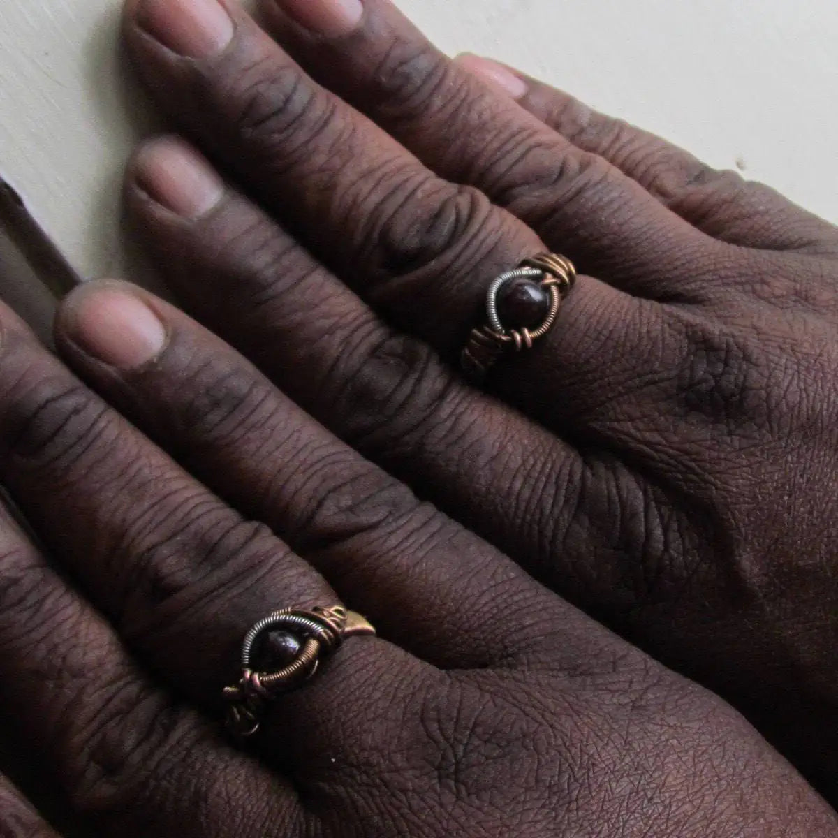 Gender neutral wire wrapped garnet ring shown on female and male hands to demonstrate fit and scale