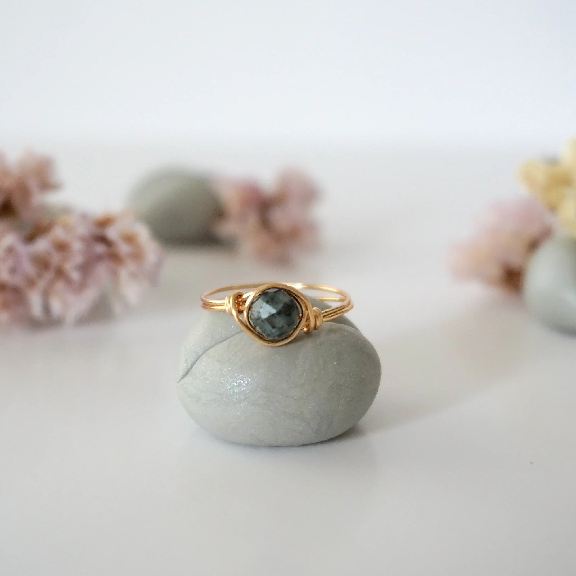 Front view of minimalist gold emerald ring with natural faceted emerald bead and artisan wire wrapping.