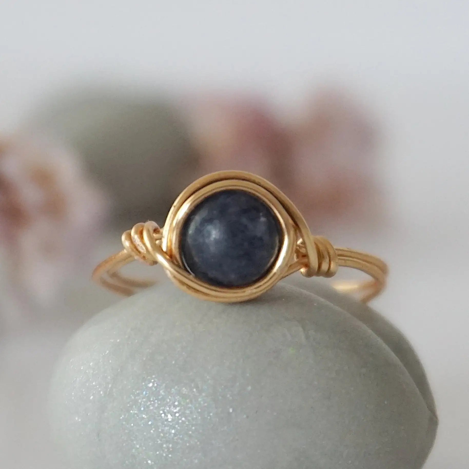 Front-angle detail of gold wire-wrapped sapphire ring showing the classic minimalist artisan setting for women