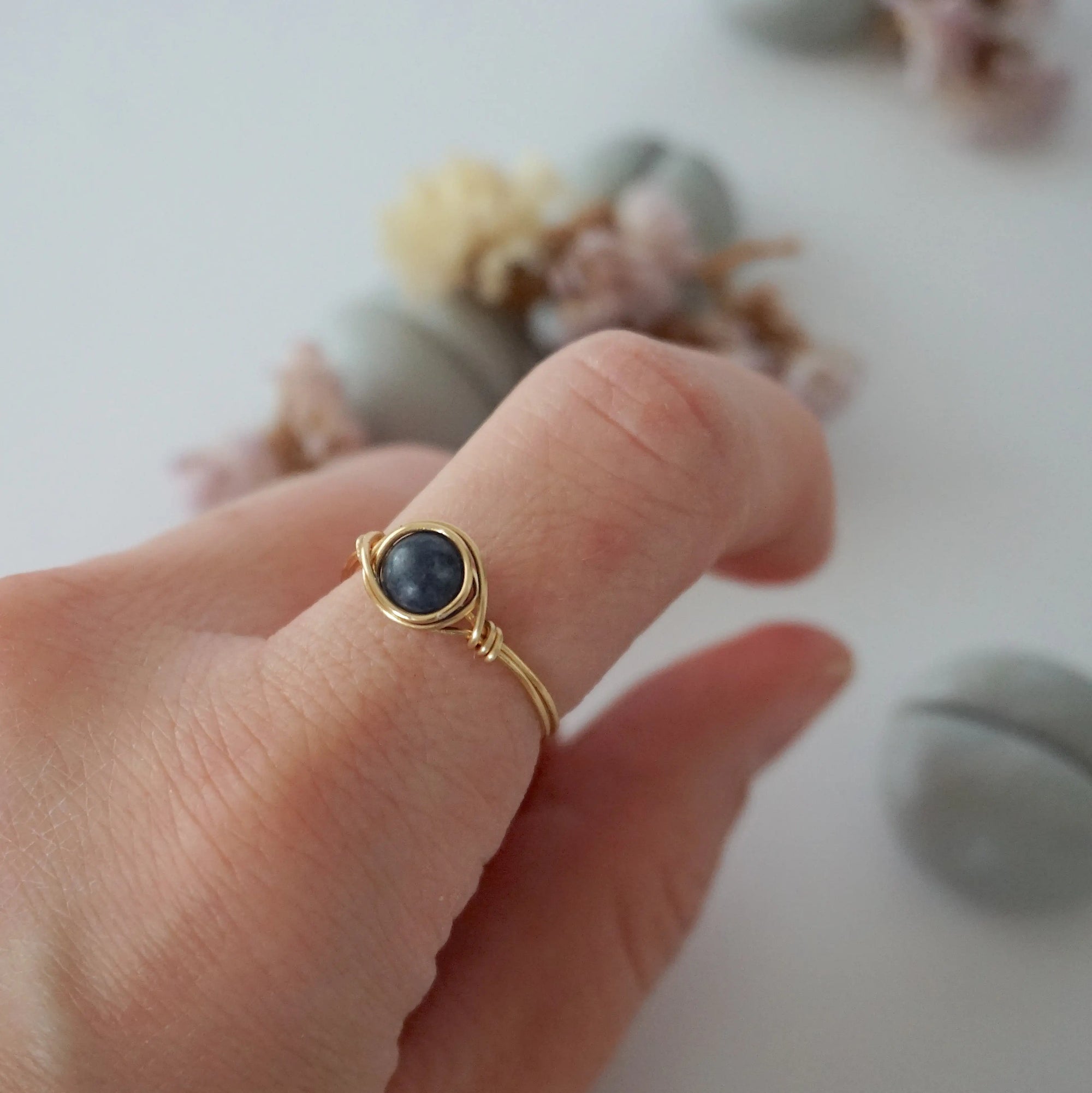 Woman wearing a minimalist gold wire-wrapped sapphire birthstone ring — handcrafted women's jewelry by Designs by Nature Gems