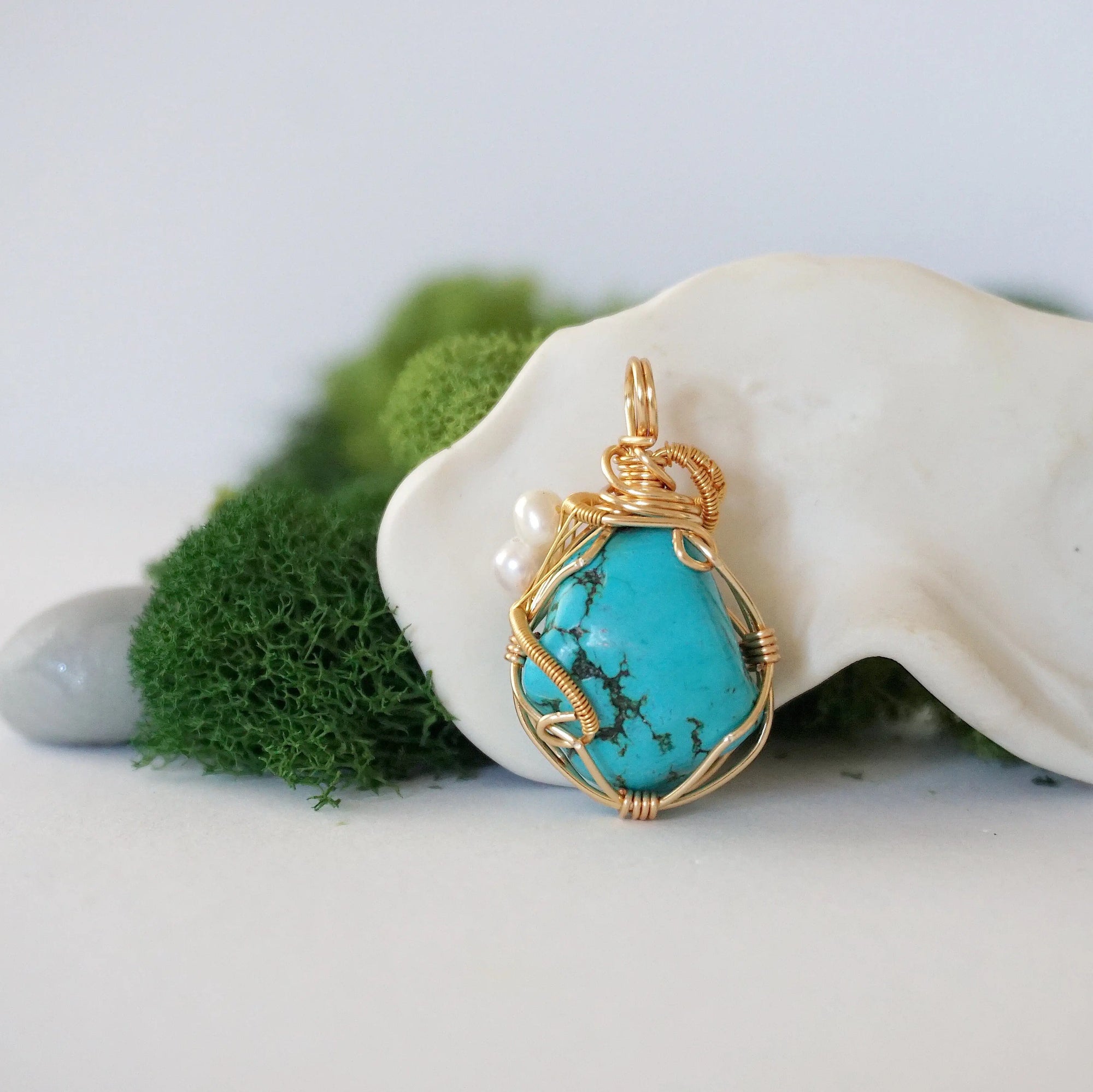 Back view of gold plated copper wire wrapped turquoise pearl pendant showing handmade wire technique
