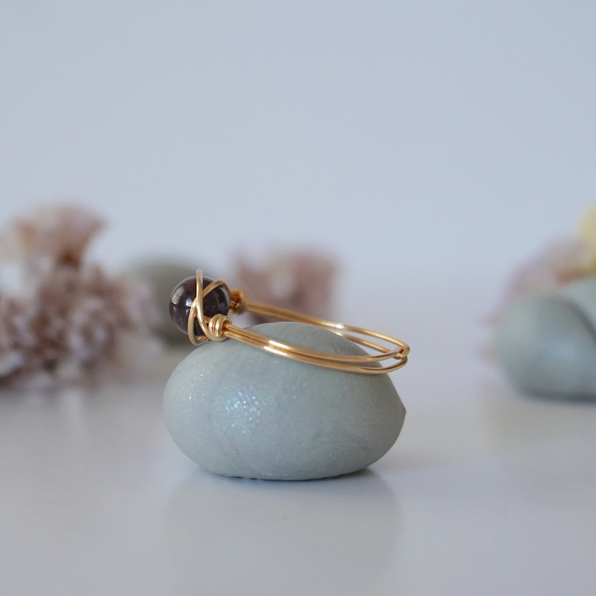 Side view of dainty garnet ring showing minimalist gold wire wrap and polished garnet bead