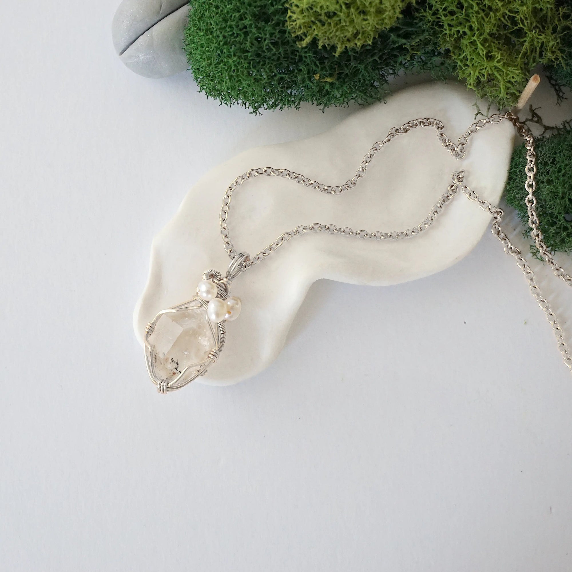 Handmade silver wire wrapped herkimer diamond and freshwater pearl necklace laying flat on a silver plated chain, artisan jewelry for women