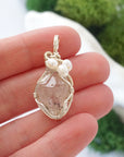 Herkimer diamond and freshwater pearl pendant necklace in hand for size reference, silver wire wrapped, handcrafted gemstone jewelry