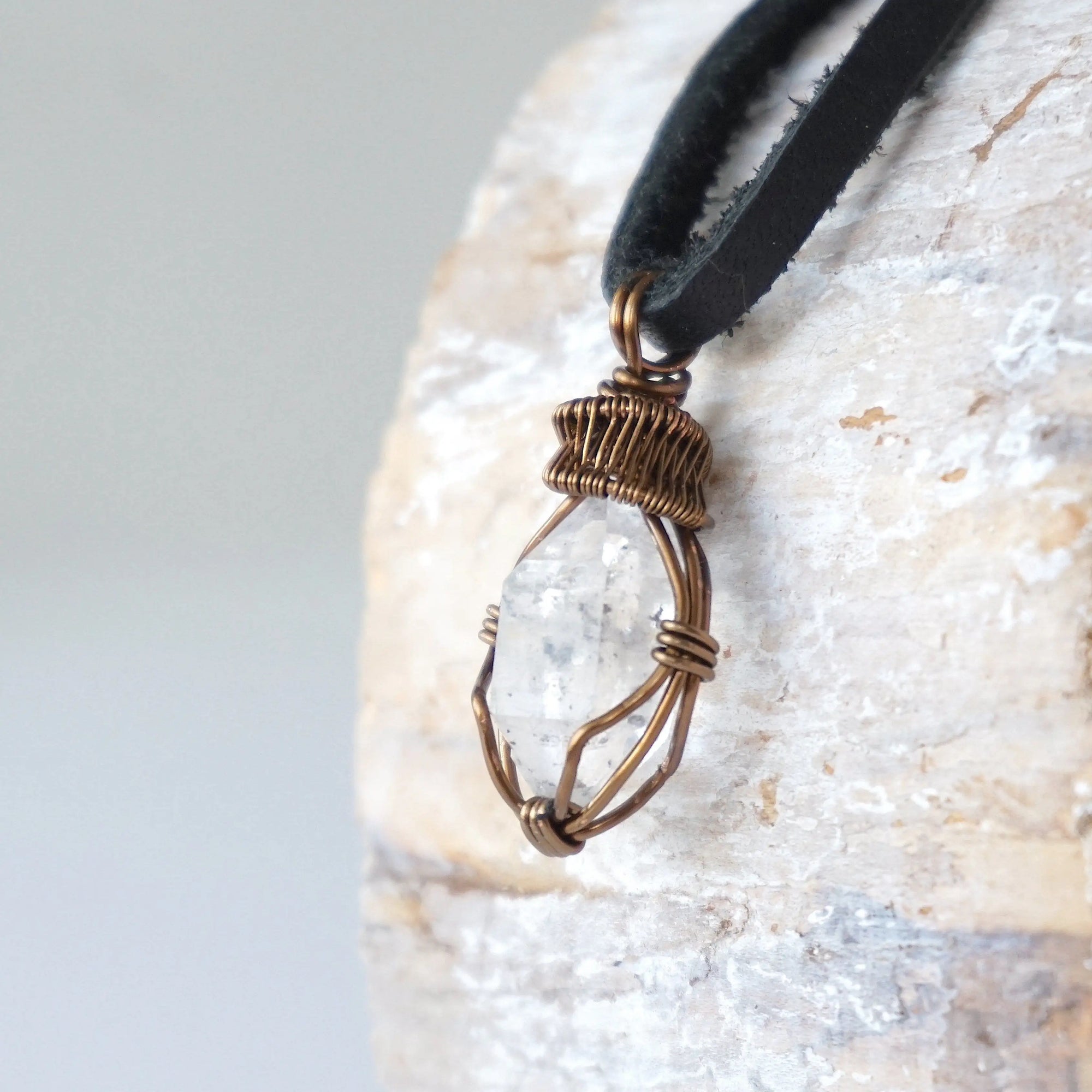 Left angle view of handmade Herkimer diamond pendant for men highlighting antique bronze copper wire artistry.