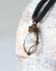 Left angle view of handmade Herkimer diamond pendant for men highlighting antique bronze copper wire artistry.