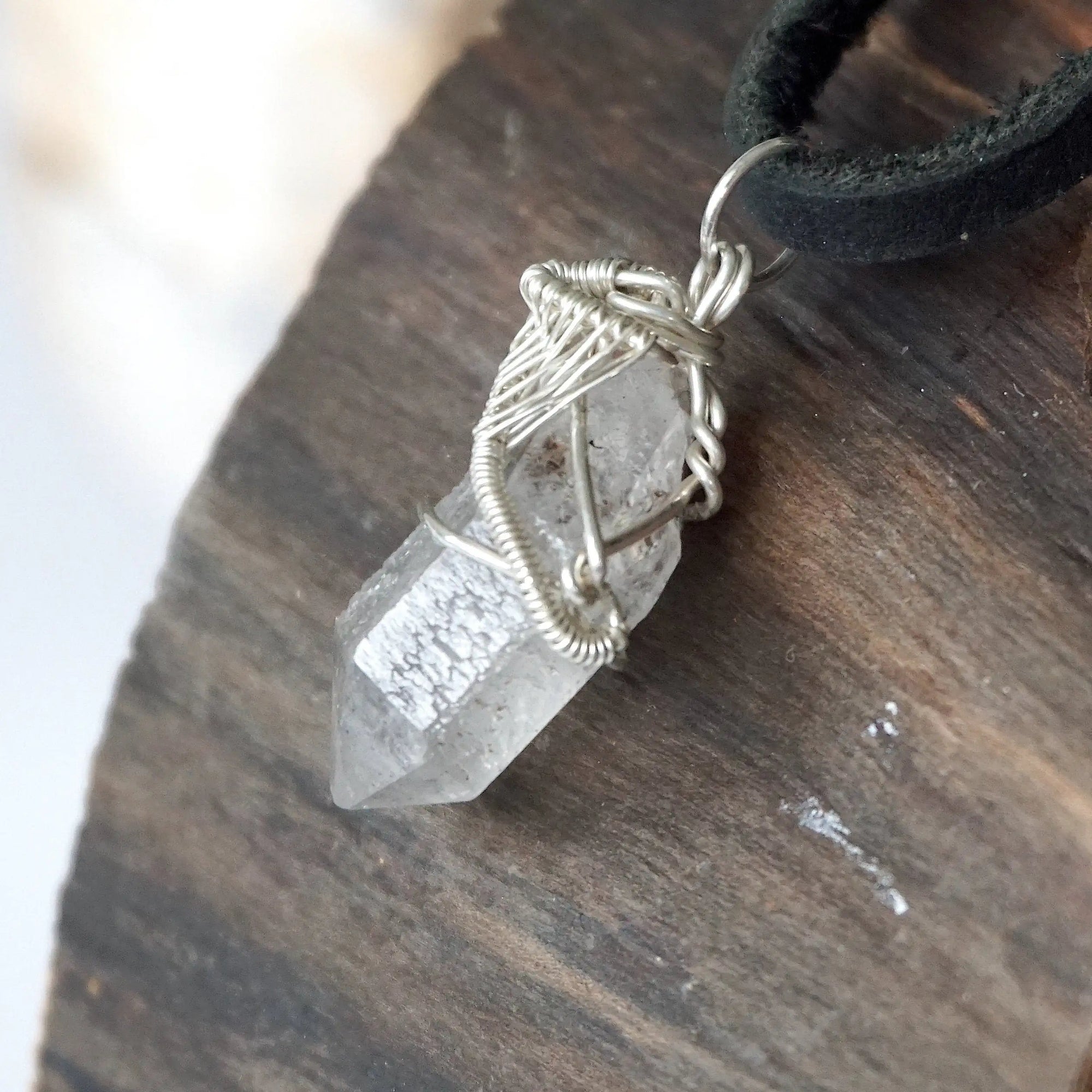 Left angle view of handmade Herkimer diamond pendant for men highlighting sterling silver wire artistry.