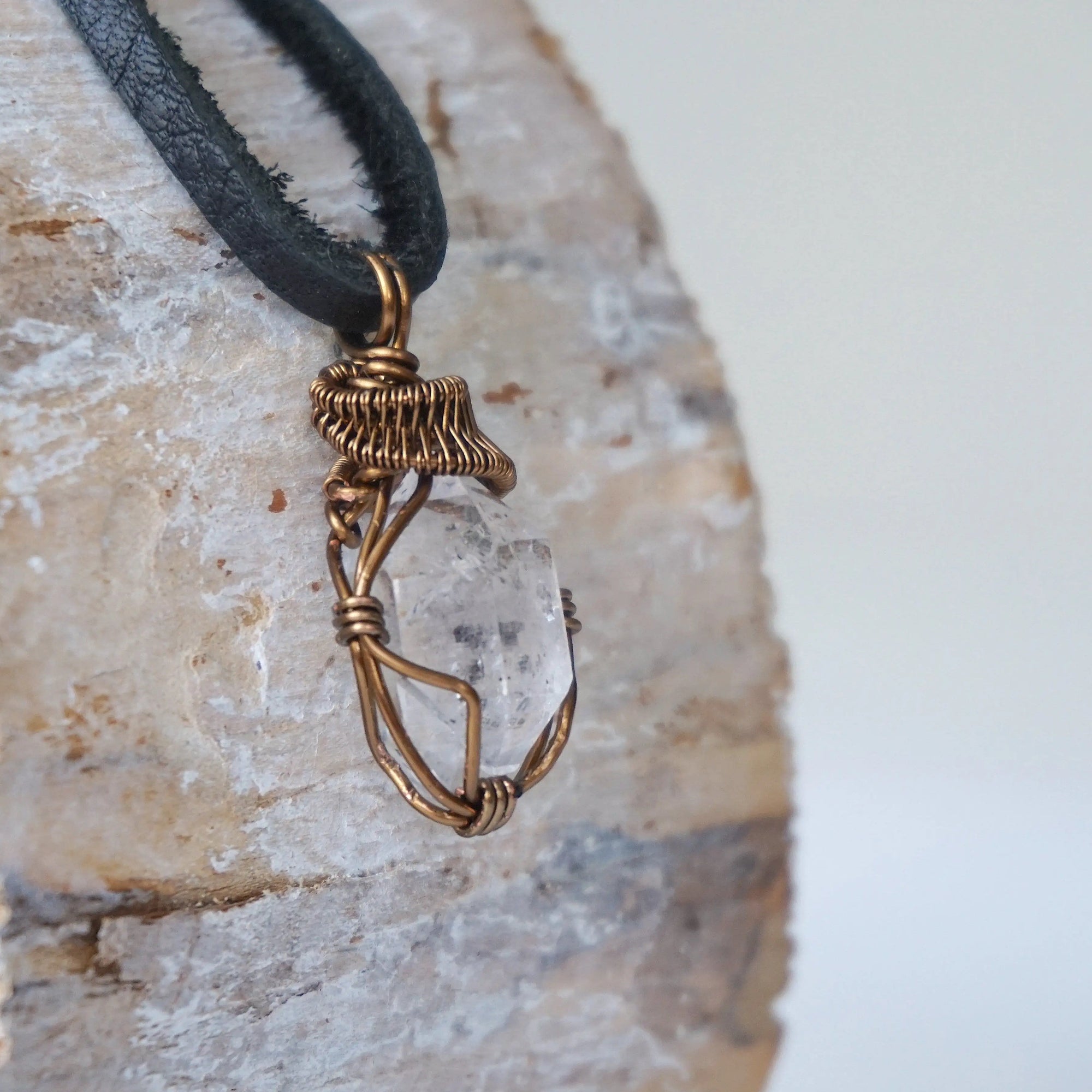 Right angle view of raw Herkimer diamond pendant for men showing detailed artisan wire wrapping in antique bronze copper.