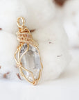 Right angle view of raw Herkimer diamond pendant showing detailed artisan wire wrapping in warm gold copper.