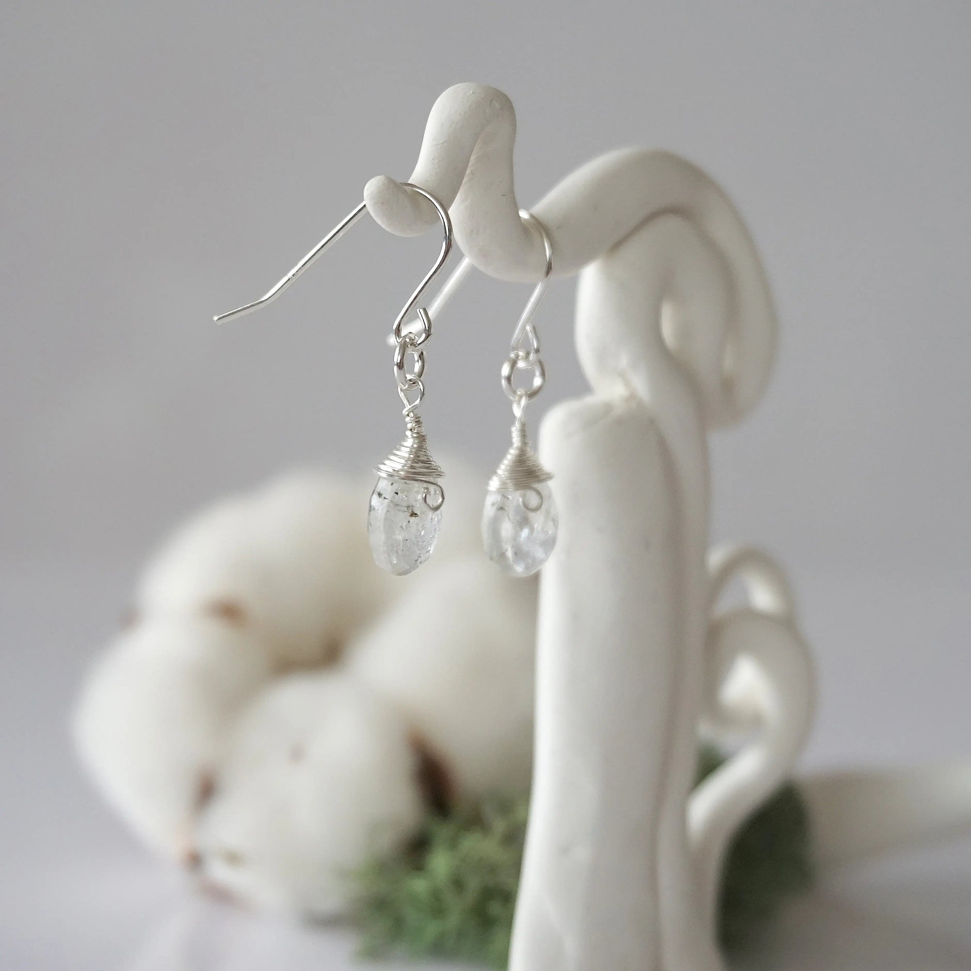 Side view of Herkimer diamond sterling silver drop earrings showing wire wrapped natural faceted Herkimer diamond, artisan craftsmanship, on a display – Designs by Nature Gems