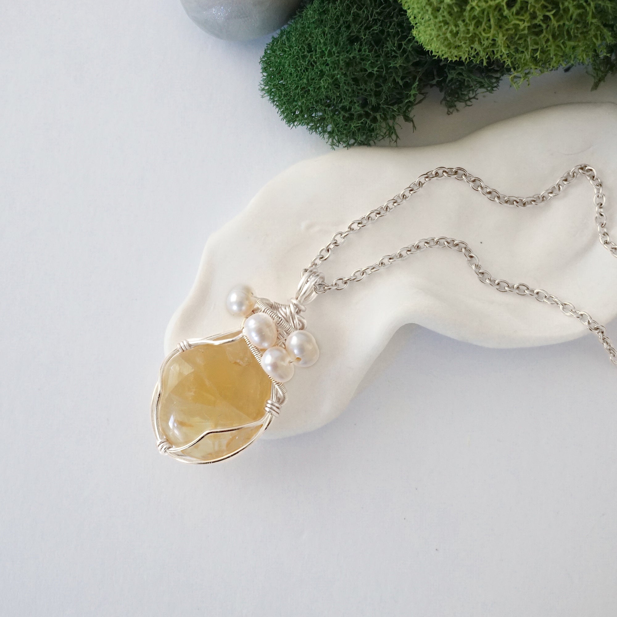 Handmade silver wire wrapped citrine and freshwater pearl necklace laying flat on a silver plated chain, artisan jewelry for women