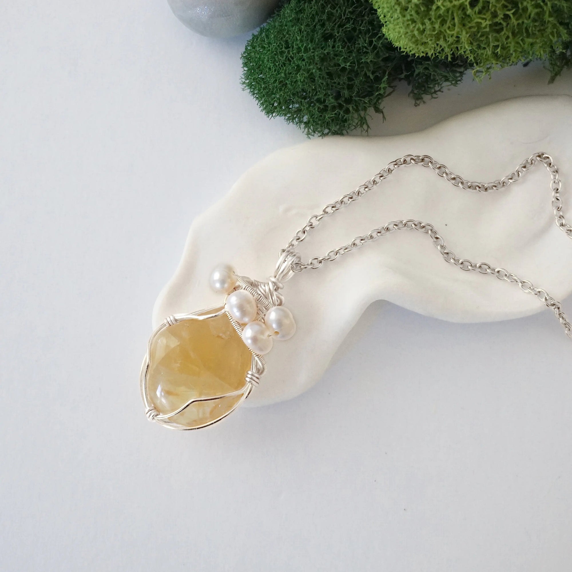 Handmade silver wire wrapped citrine and freshwater pearl necklace laying flat on a silver plated chain, artisan jewelry for women