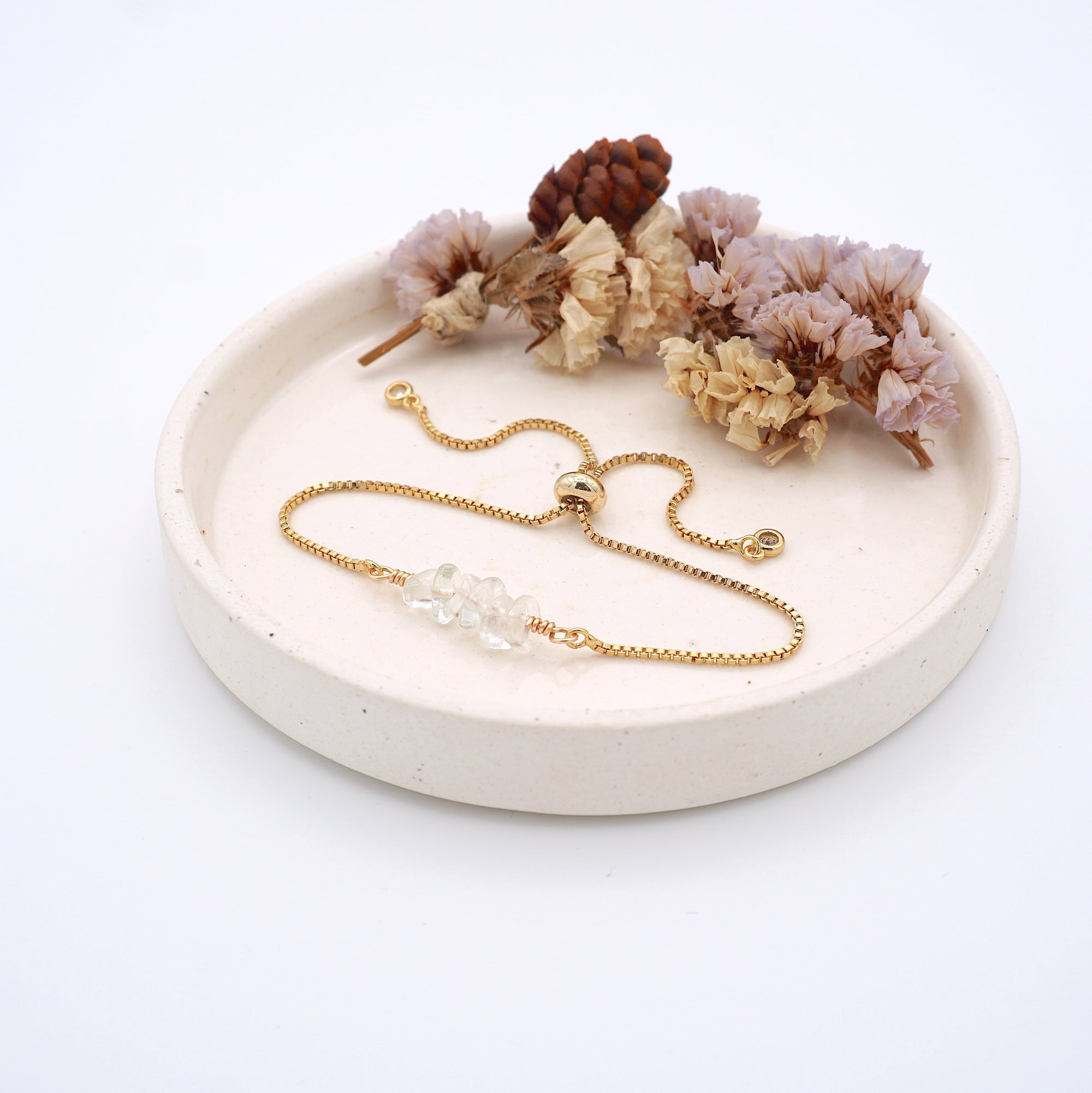 Handmade clear quartz bracelet displayed on ceramic tray showing natural crystals and gold chain - April birthstone gift for her