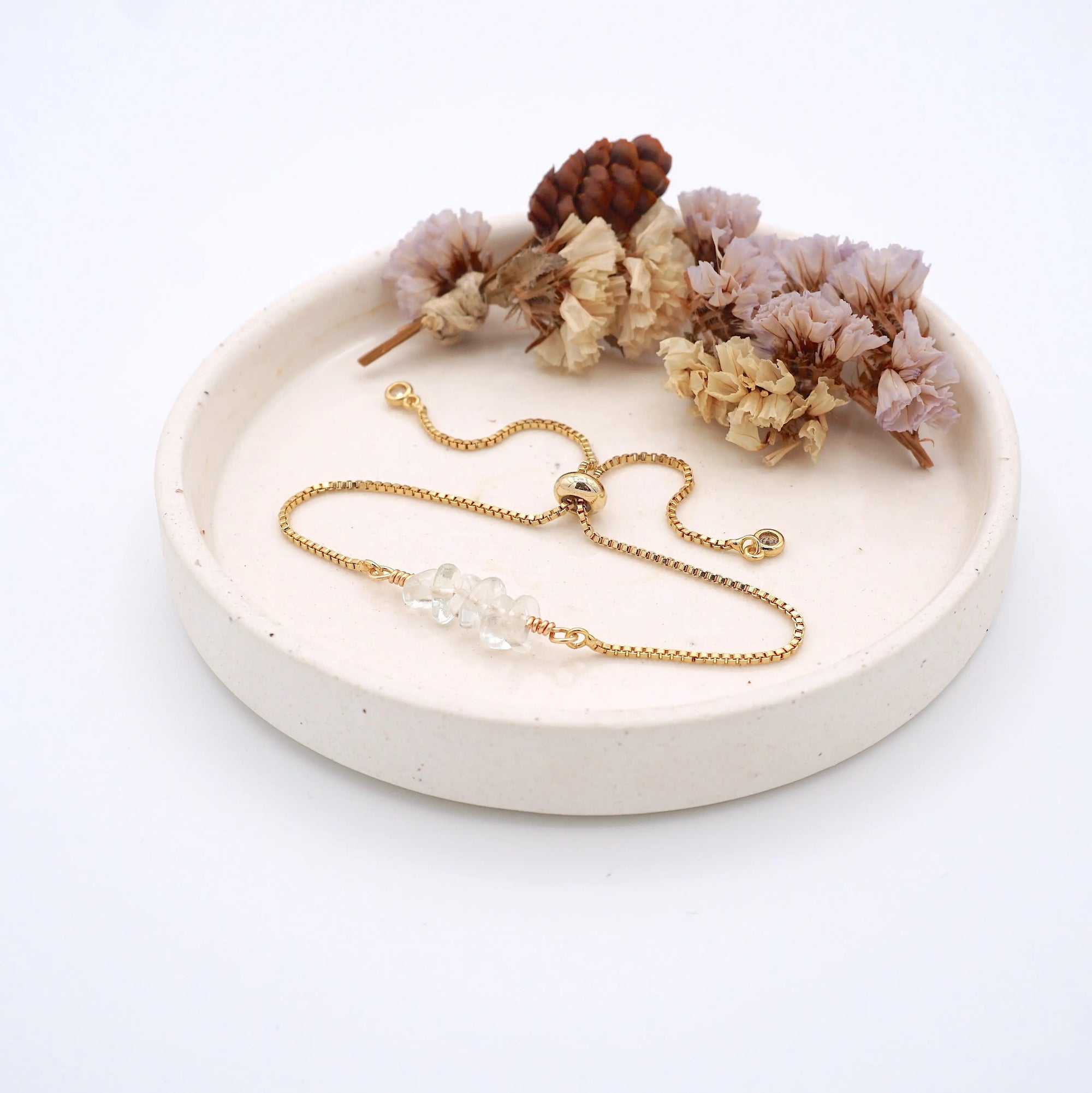 Handmade clear quartz bracelet displayed on ceramic tray showing natural crystals and gold chain - April birthstone gift for her