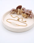 Handmade clear quartz bracelet displayed on ceramic tray showing natural crystals and gold chain - April birthstone gift for her