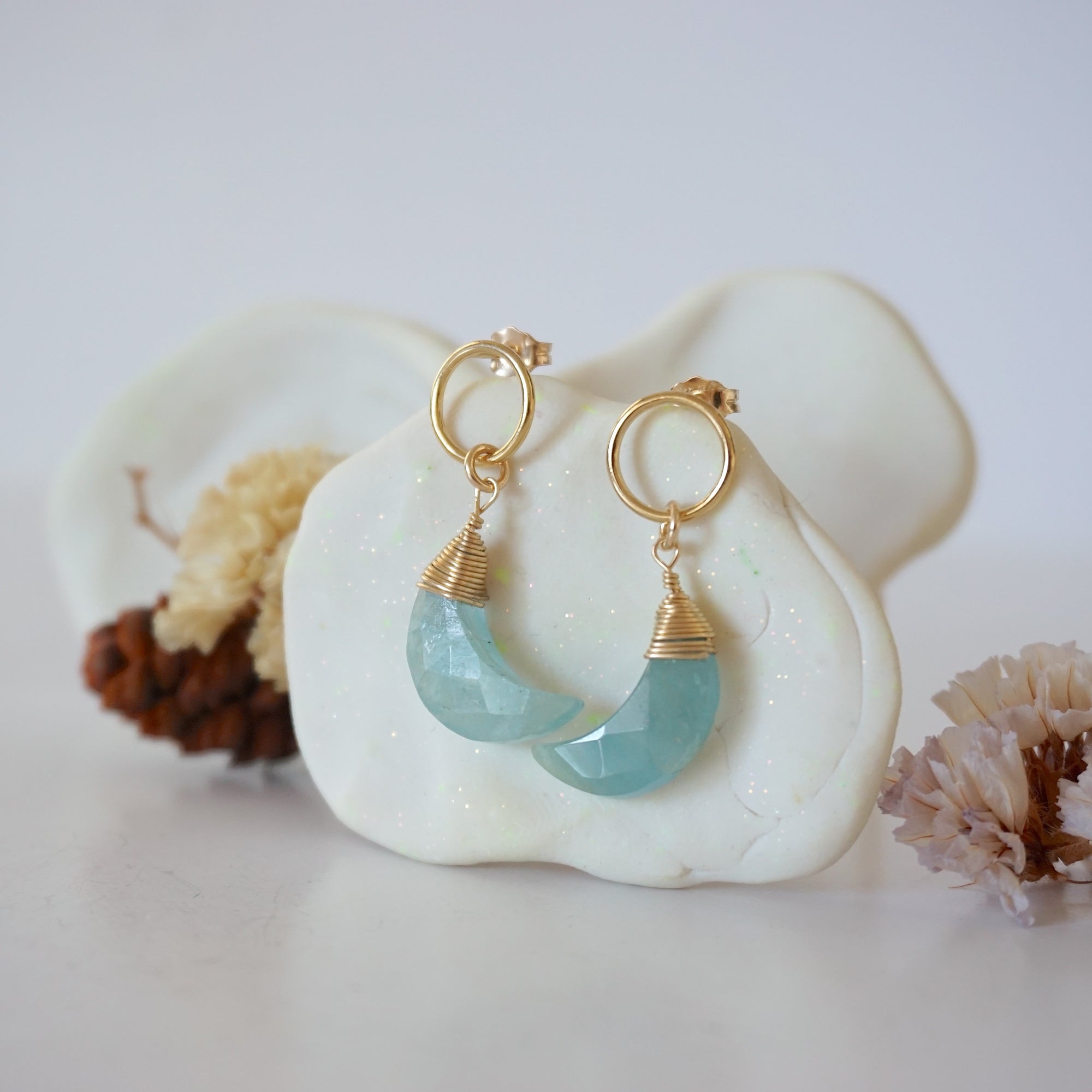 Side angle view of Aquamarine Moon Open Circle Stud Earrings hanging on jewelry display, minimalist 14k gold filled wire wrap, limited edition.