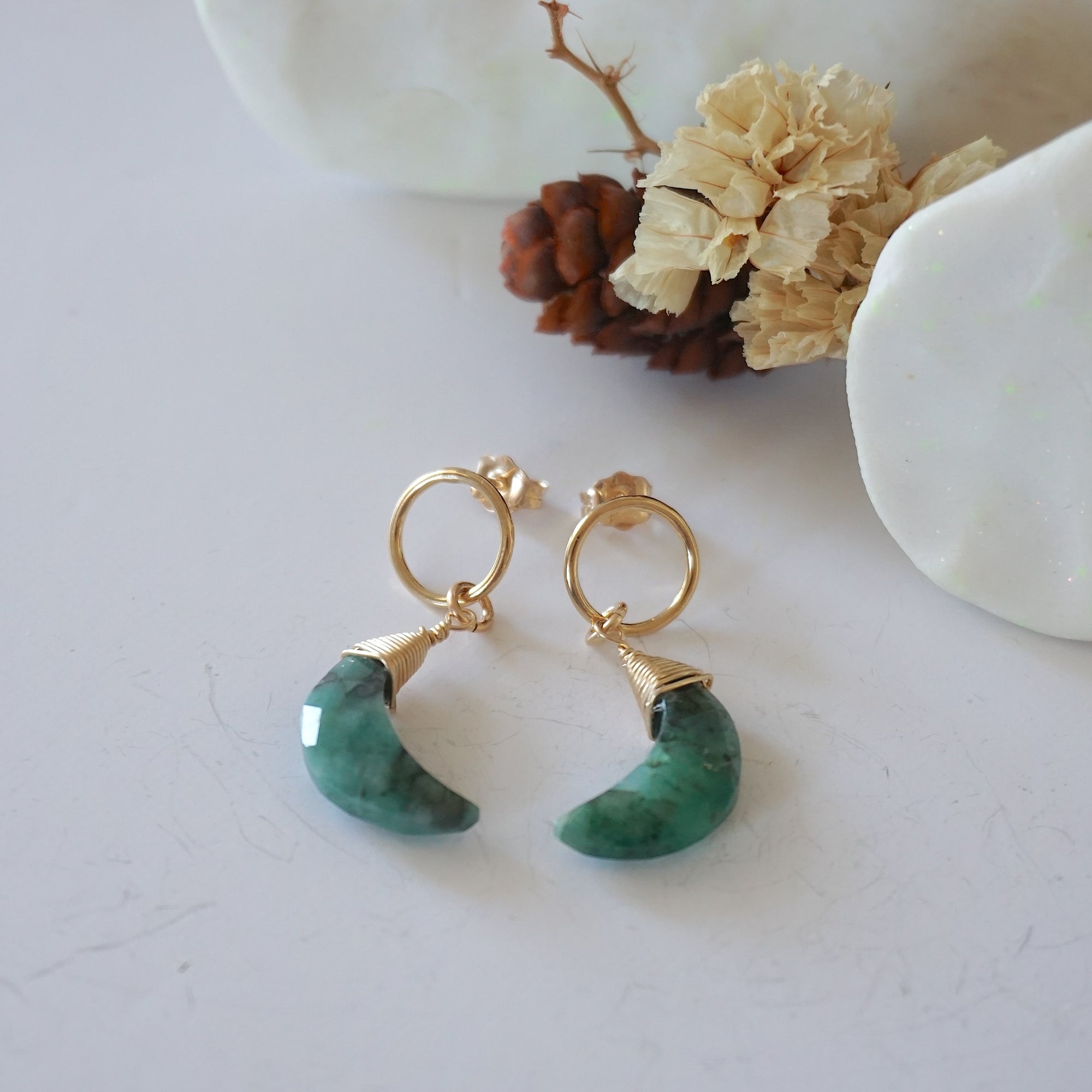 Emerald Moon Open Circle Stud Earrings laying flat, 14k gold filled minimalist wire wrap, natural faceted emerald, limited edition.