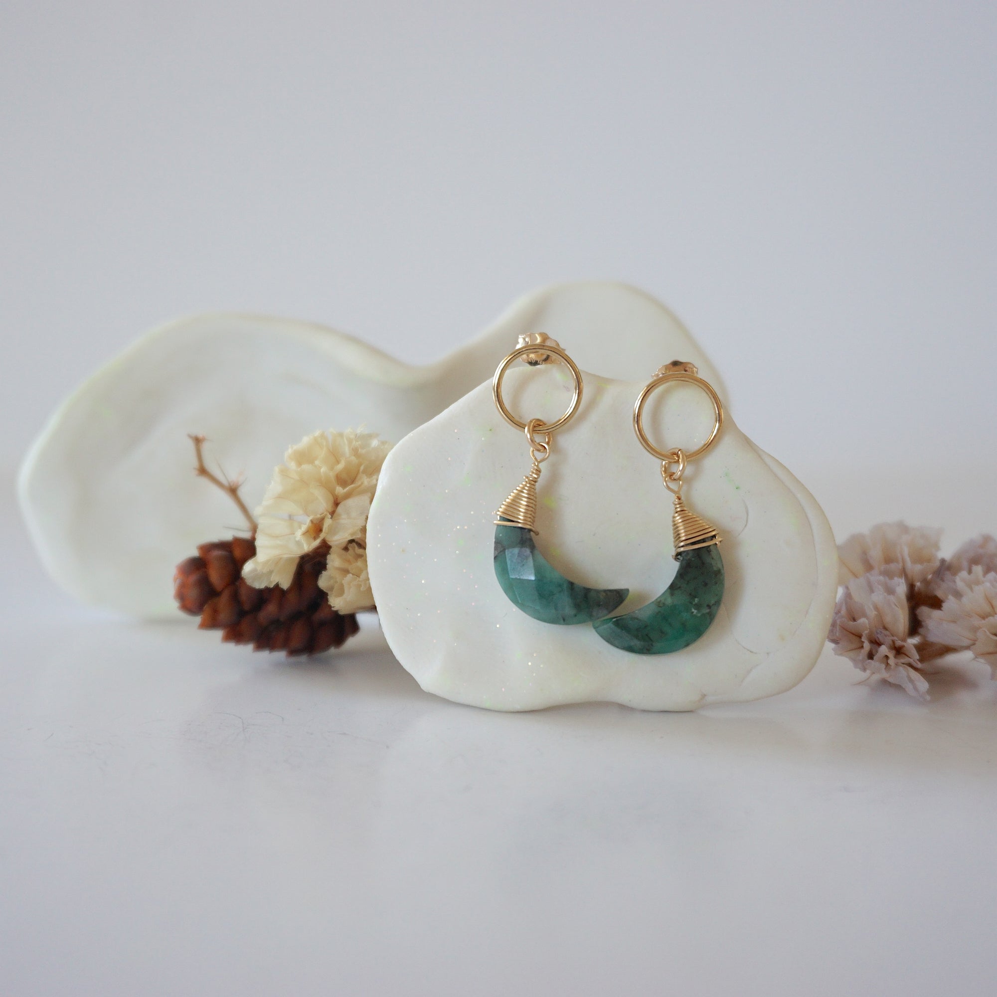 Front angle look at Lux Emerald Moon Open Circle Stud Earrings on jewelry display, faceted natural emerald, gold filled, handmade.