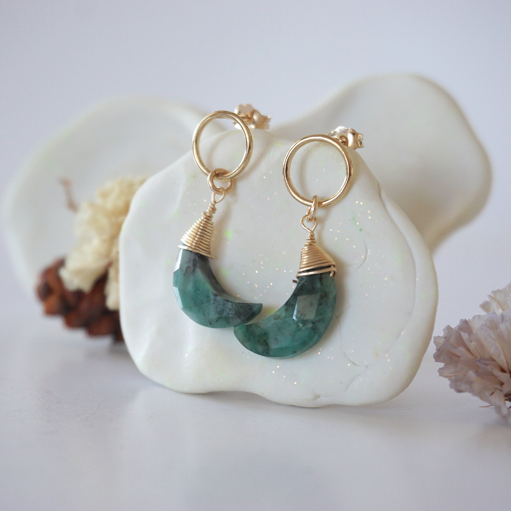 Side angle view of Emerald Moon Open Circle Stud Earrings hanging on jewelry display, minimalist 14k gold filled wire wrap, limited edition.