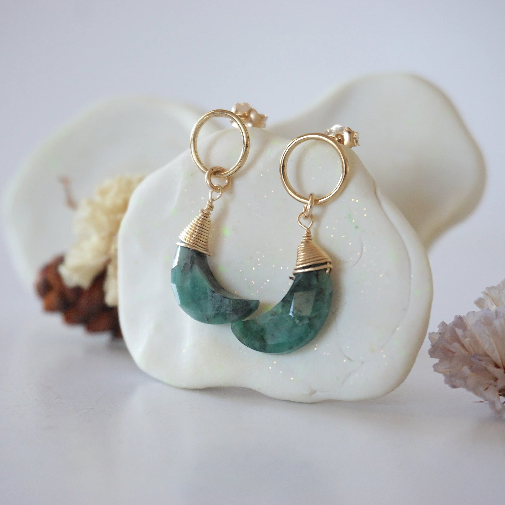 Side angle view of Emerald Moon Open Circle Stud Earrings hanging on jewelry display, minimalist 14k gold filled wire wrap, limited edition.