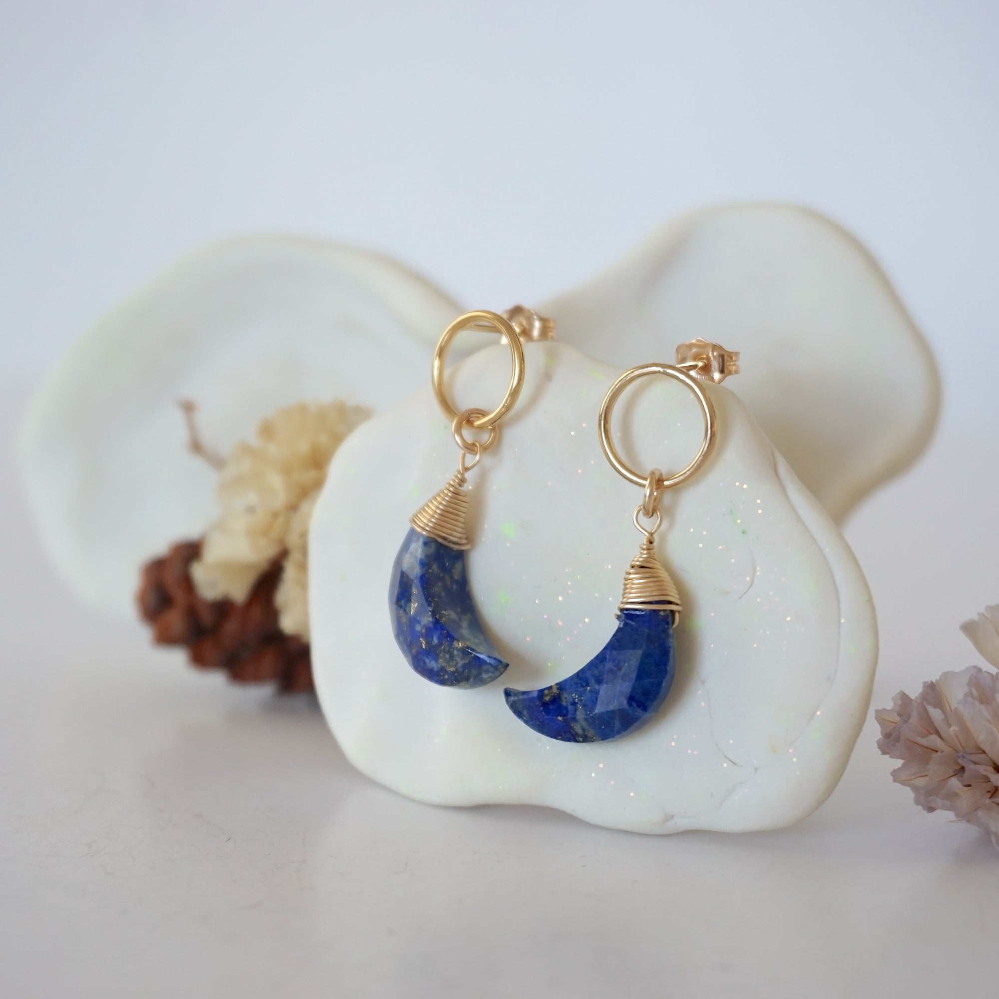 Side angle view of Lapis Lazuli Moon Open Circle Stud Earrings hanging on jewelry display, minimalist 14k gold filled wire wrap, limited edition.