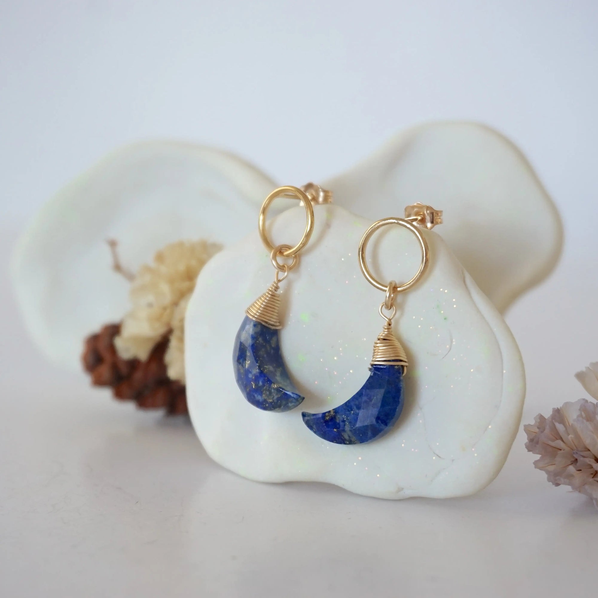 Side angle view of Lapis Lazuli Moon Open Circle Stud Earrings hanging on jewelry display, minimalist 14k gold filled wire wrap, limited edition.
