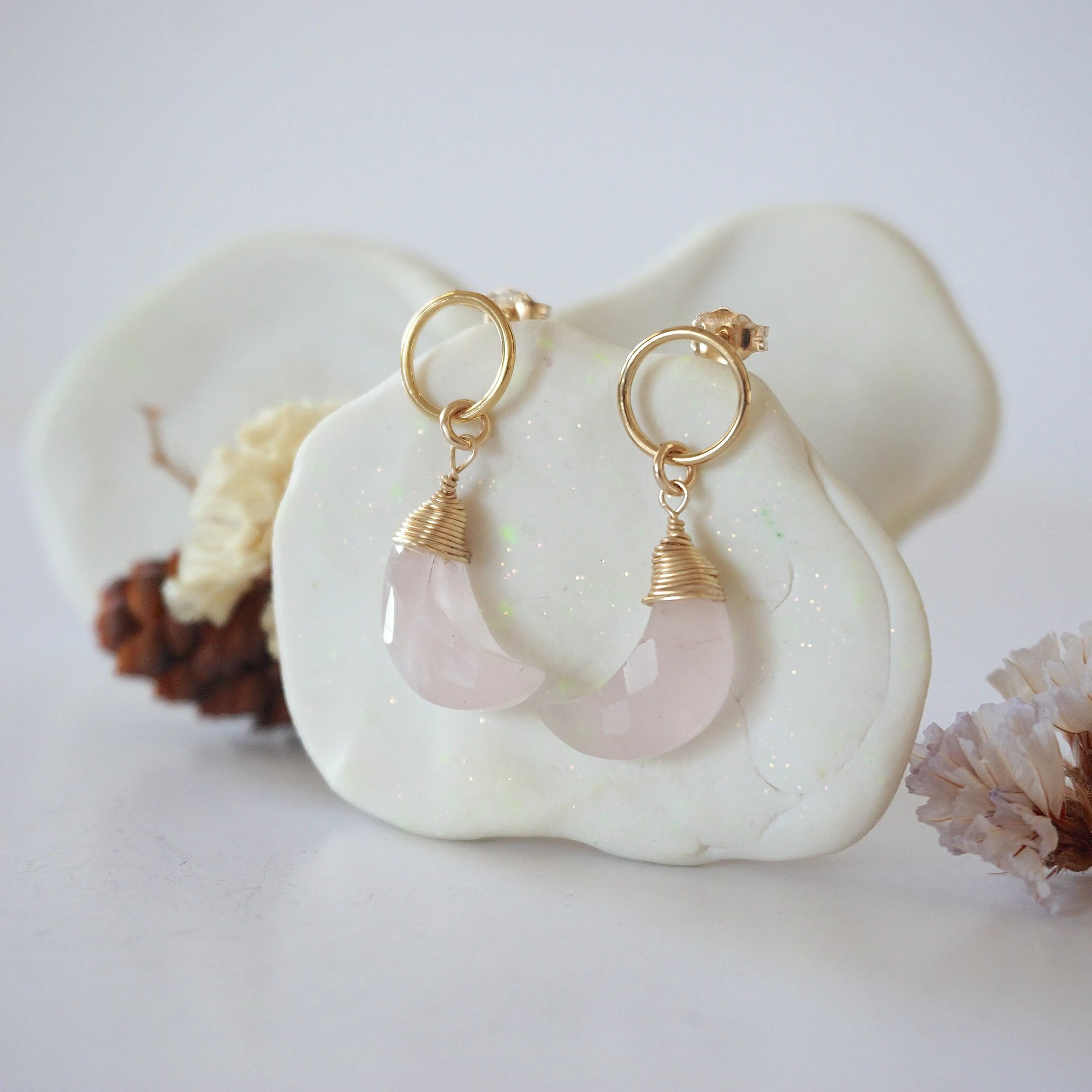 Side angle view of Rose Quartz Moon Open Circle Stud Earrings hanging on jewelry display, minimalist 14k gold filled wire wrap, limited edition.
