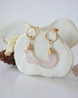 Side angle view of Rose Quartz Moon Open Circle Stud Earrings hanging on jewelry display, minimalist 14k gold filled wire wrap, limited edition.