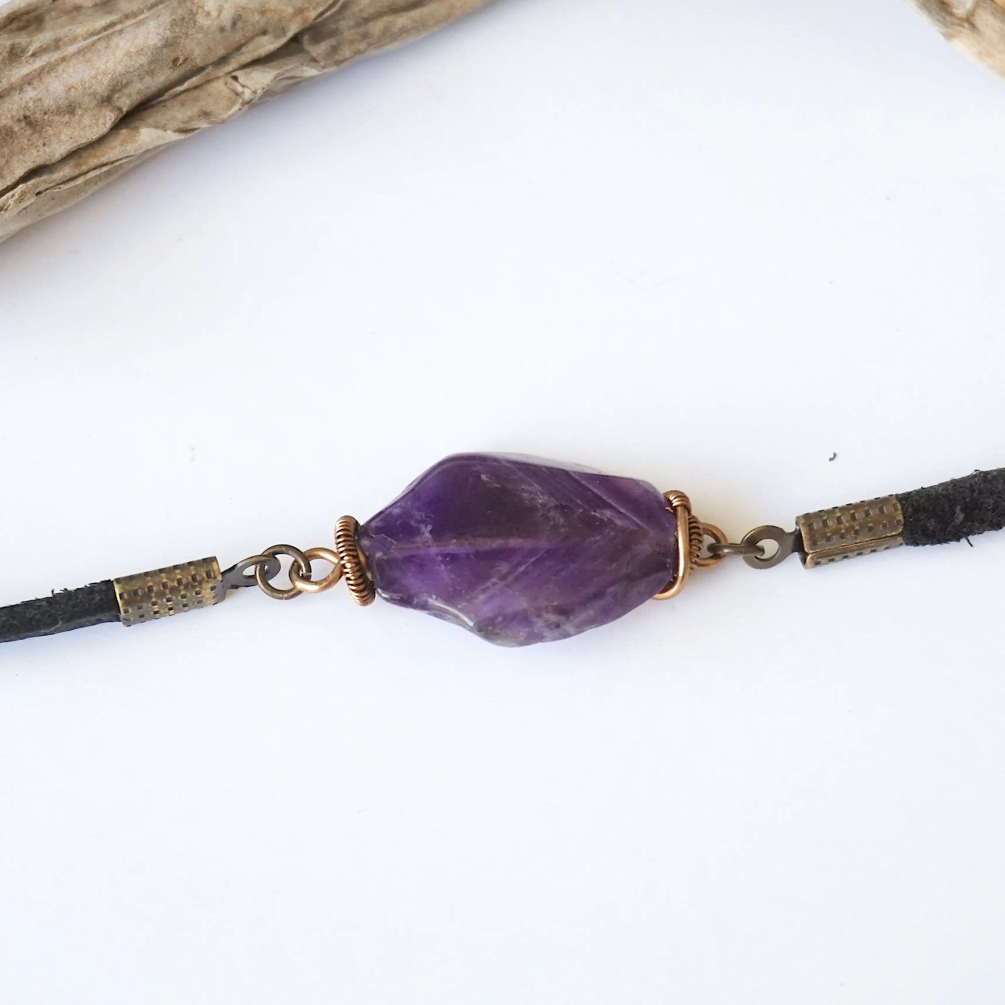 Close up of raw amethyst stone wrapped in antique bronze copper, men’s amethyst bracelet on black leather cord