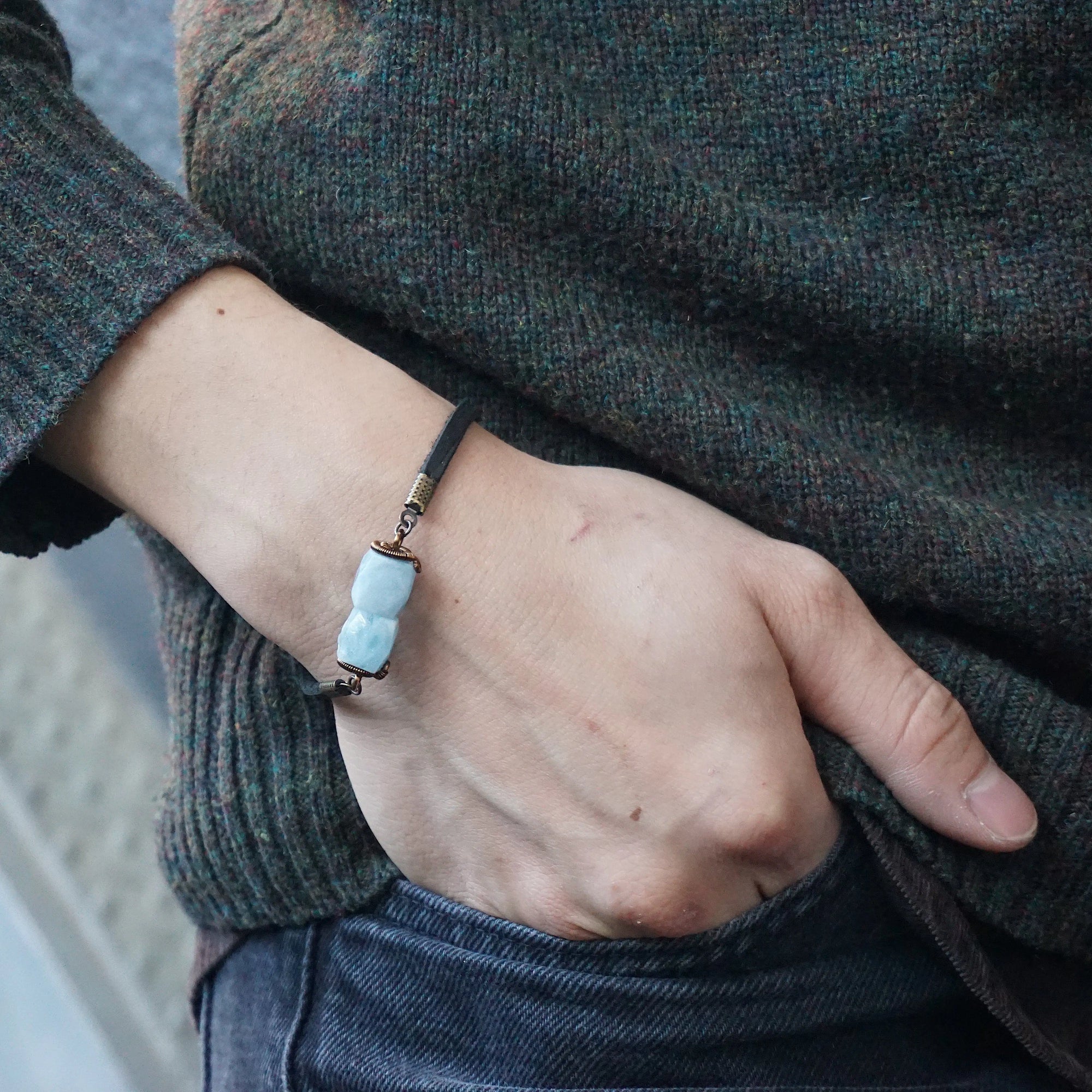 Men's aquamarine bracelet with faceted aquamarine stones, antique bronze wire, and black leather cord on male model's wrist, Designs by Nature Gems