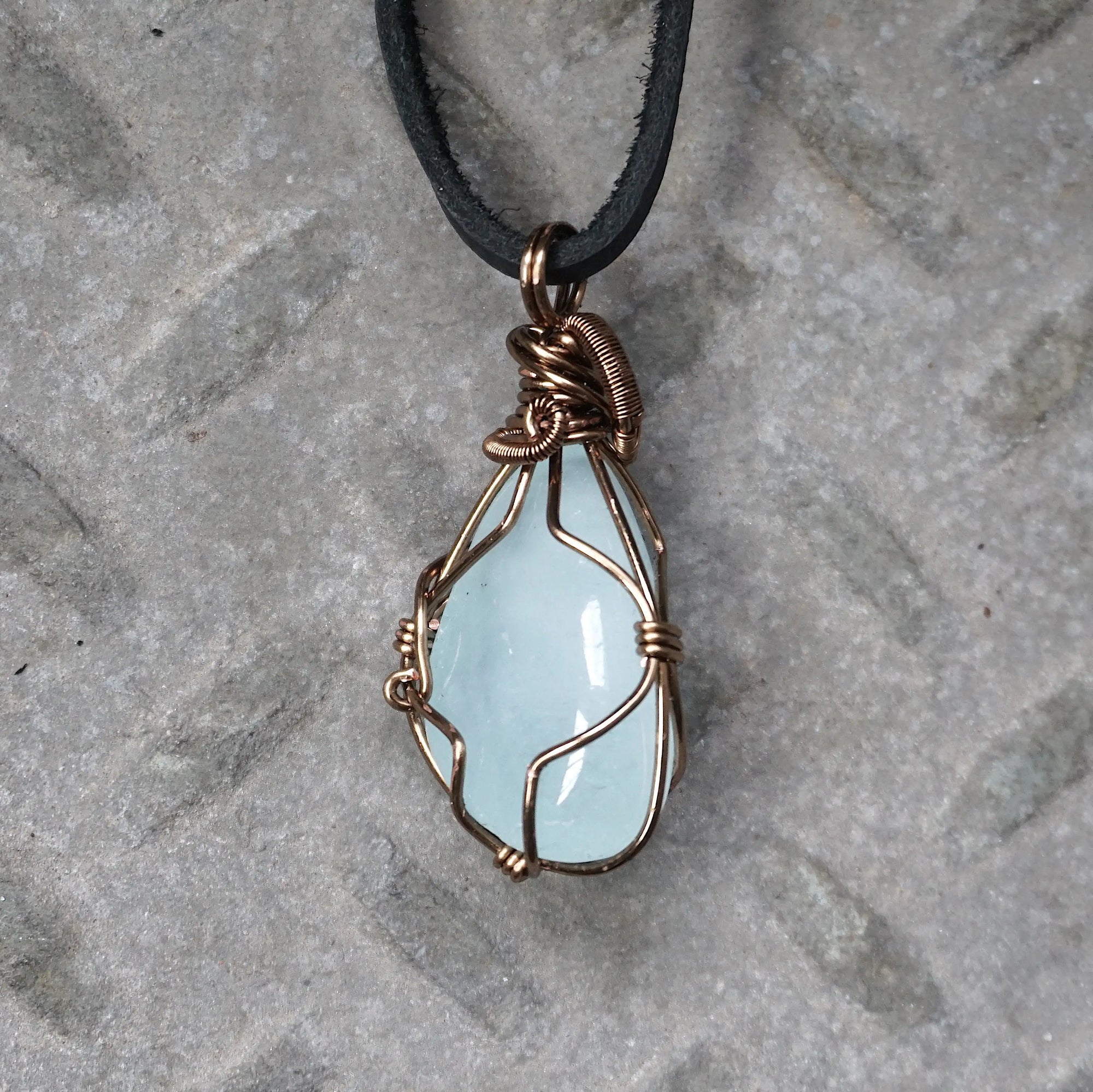 Back side angle of men's aquamarine pendant necklace, detailed wire wrapping, antique bronze copper, black leather cord