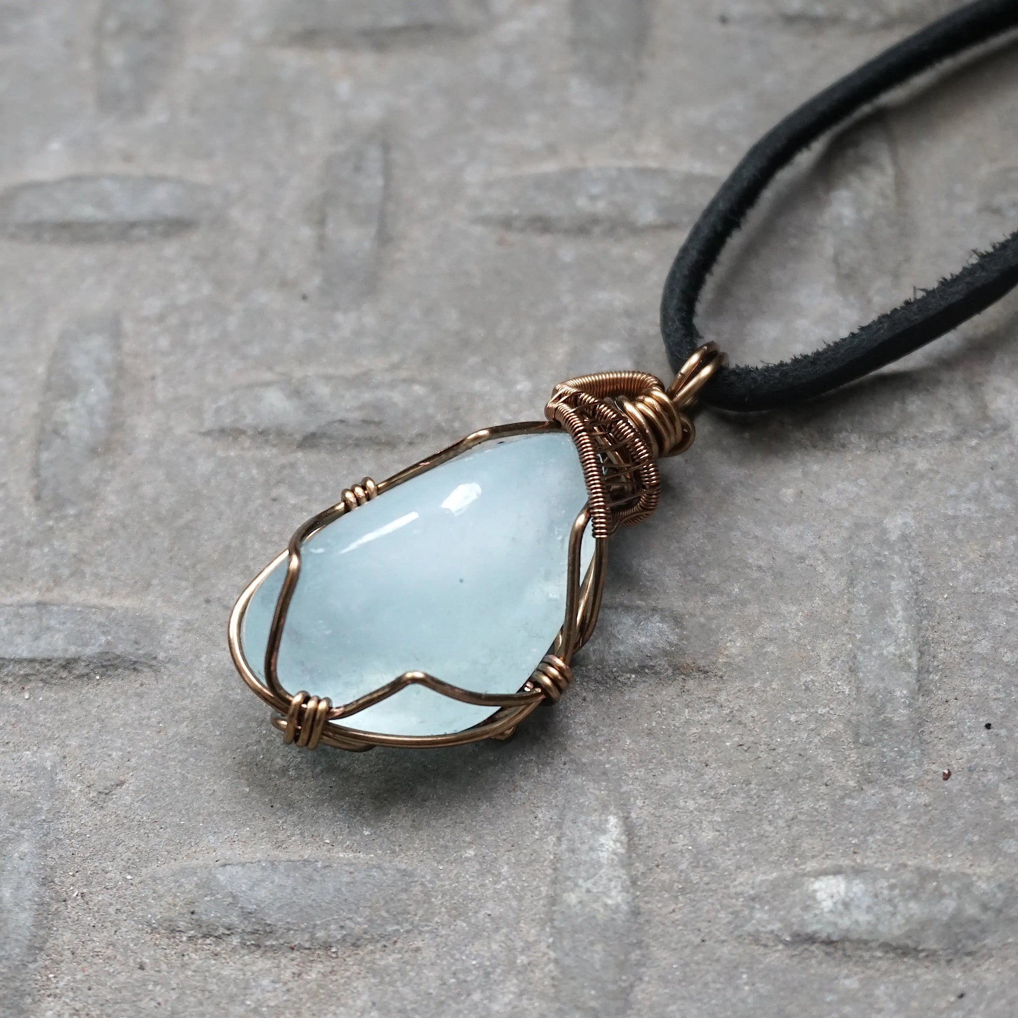 Left side angle of men's aquamarine necklace, showing artisan wire wrapping and polished aquamarine, antique bronze finish