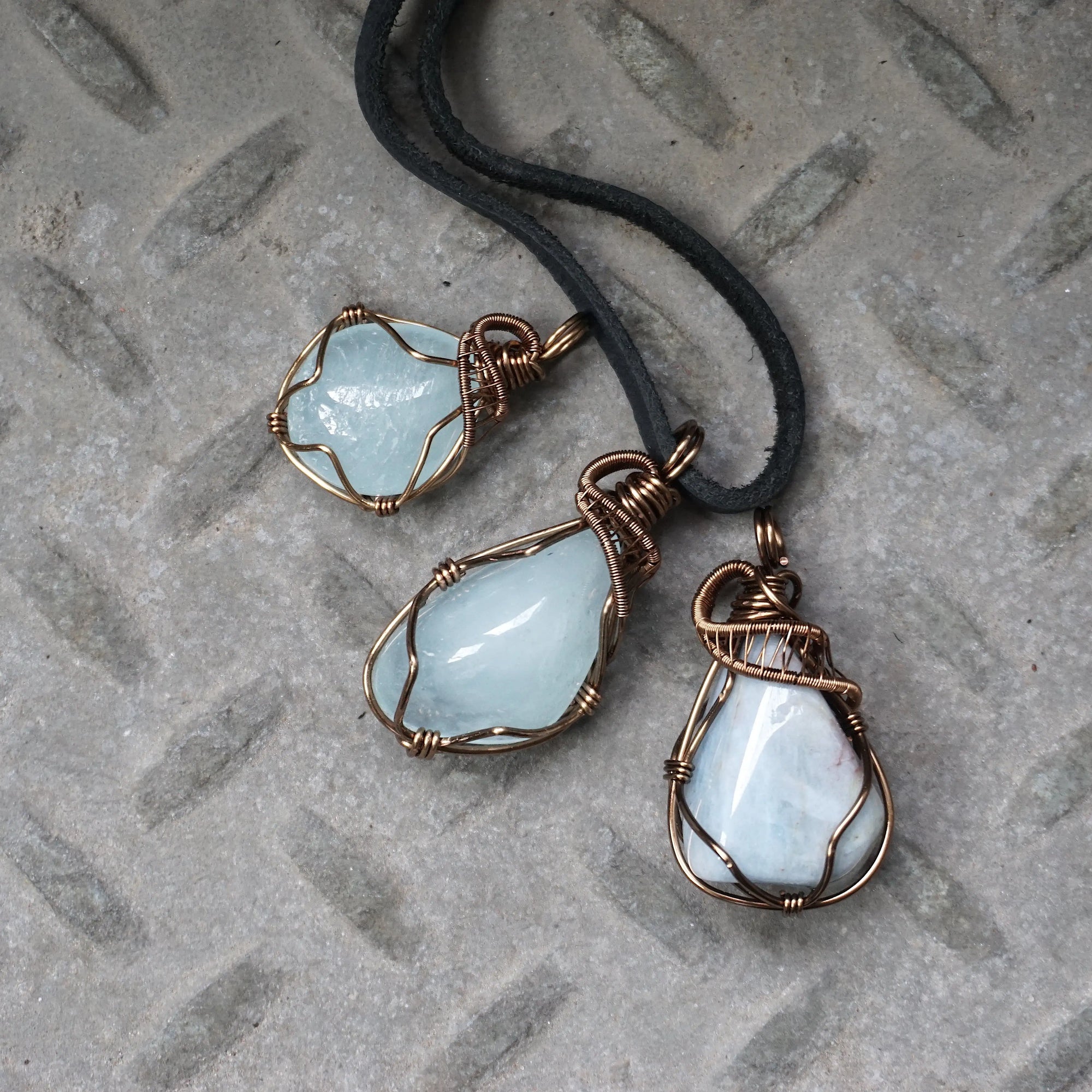 Three men's aquamarine pendants showing natural variation in aquamarine's shape, size, and blue color, Designs by Nature Gems