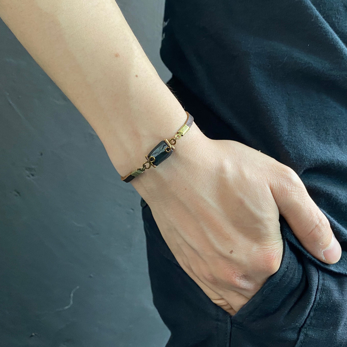 Men’s black tourmaline bracelet in antique bronze and brown leather, worn on the wrist