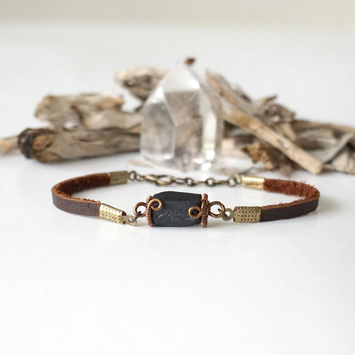 Full view of a black tourmaline bracelet with genuine brown leather band and bronze chain extension