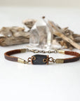 Full view of a black tourmaline bracelet with genuine brown leather band and bronze chain extension