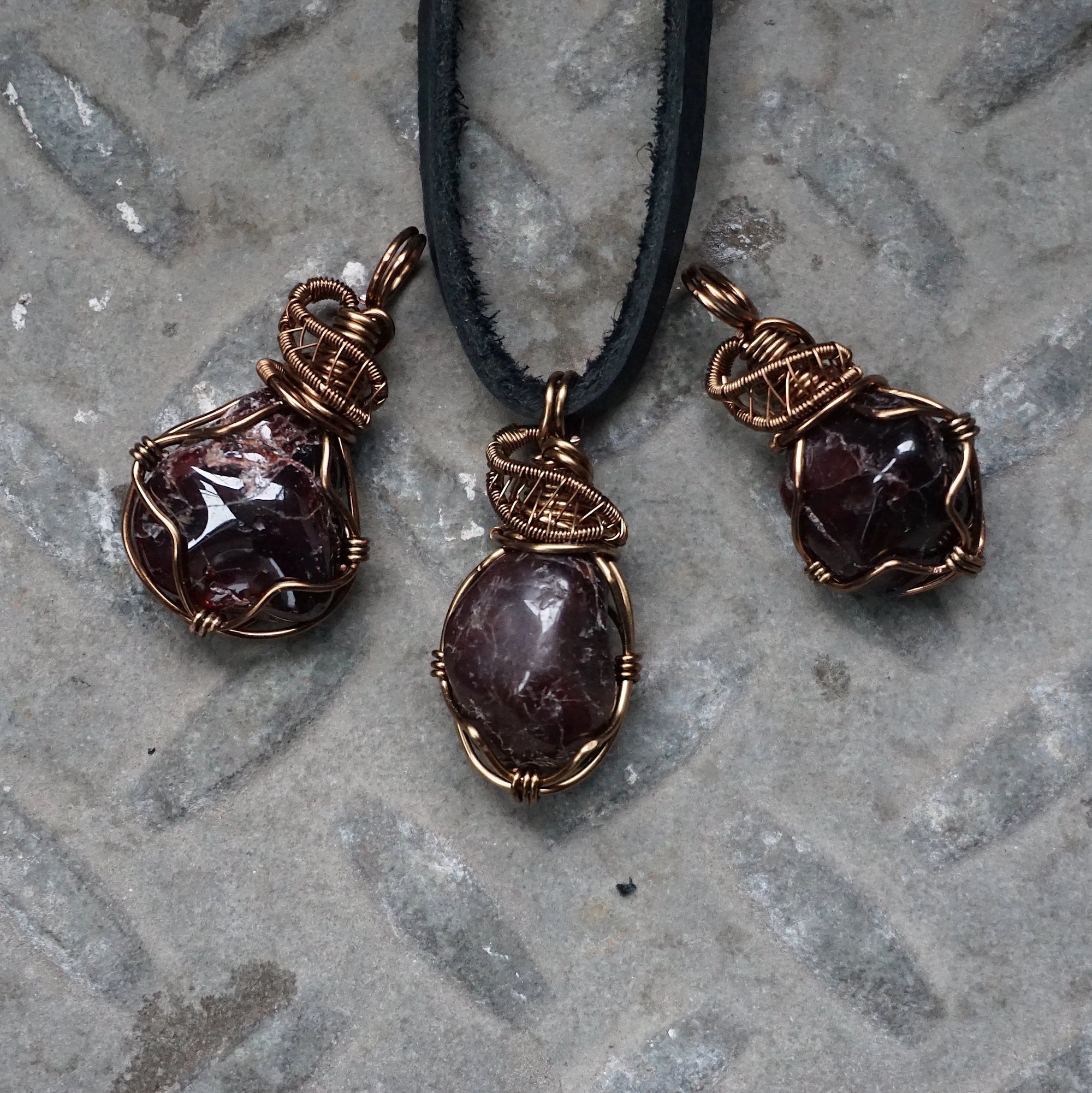 Three natural garnet pendants showing variation in size, shape, and color, allowing customers to choose their men’s wire wrapped garnet necklace