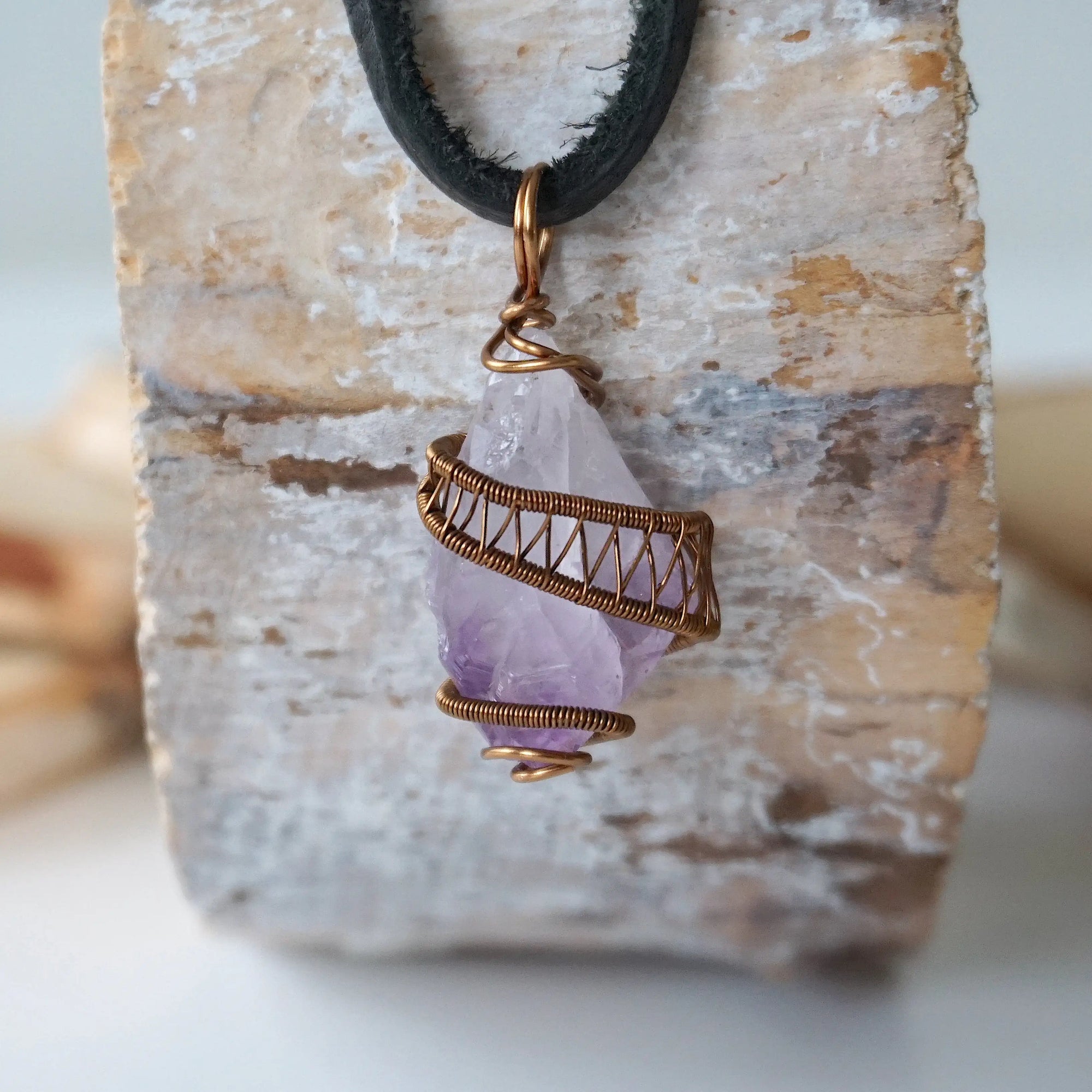 Front view of men’s raw amethyst crystal pendant wire wrapped in antique bronze copper on black leather cord, February birthstone