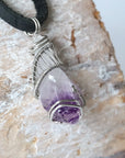 Right side angle of men’s raw amethyst pendant wire wrapped in white gold plated copper on black leather cord