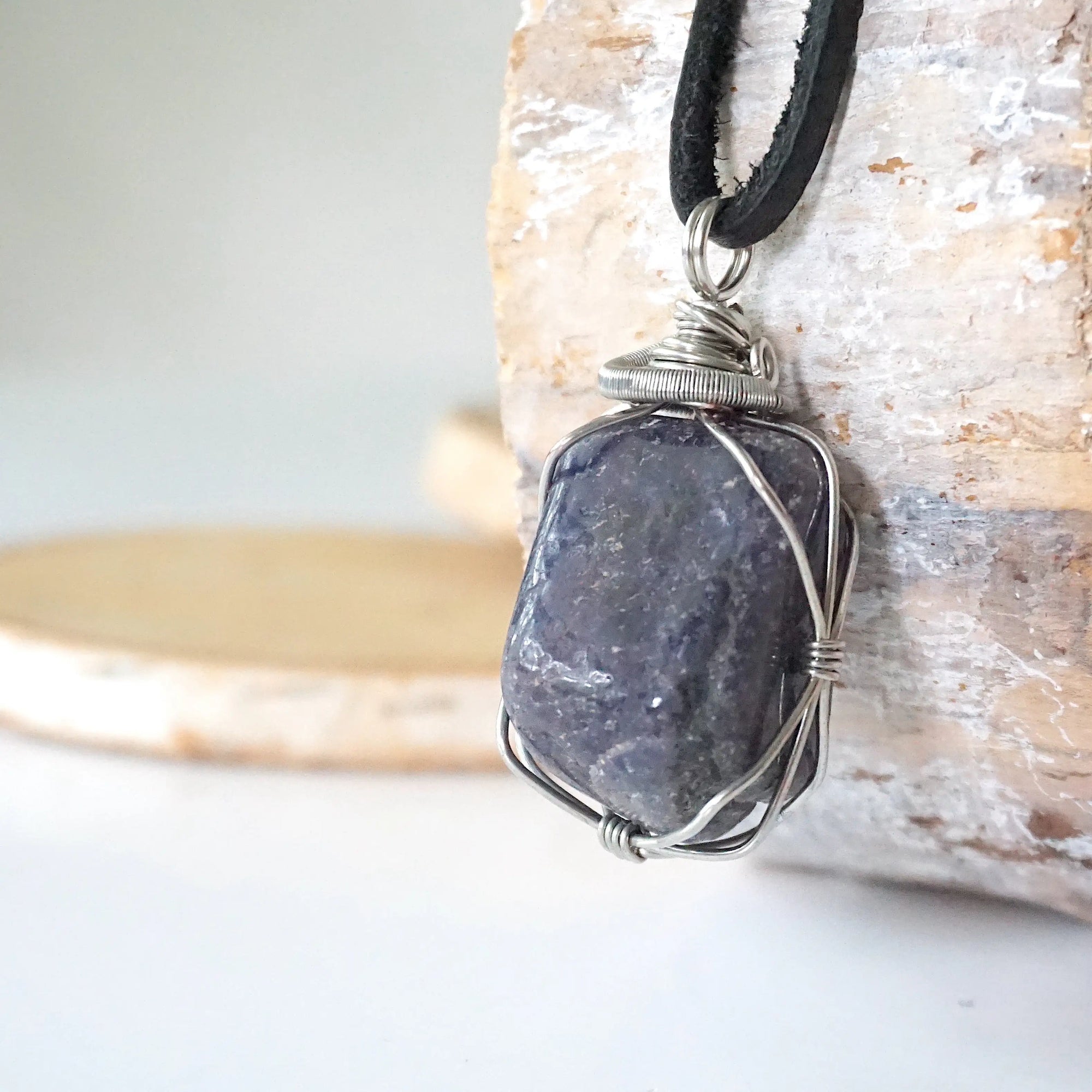 Left-angle close-up of natural sapphire pendant revealing the precision of dark silver wire-wrapping craftsmanship — men's artisan crystal jewelry