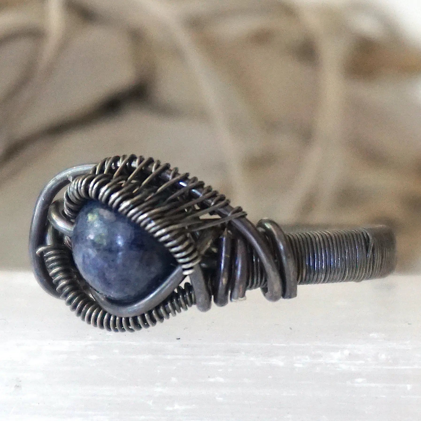 Front view of men's natural 8mm sapphire ring focused on the stone and antiqued 925 sterling silver wire wrapping