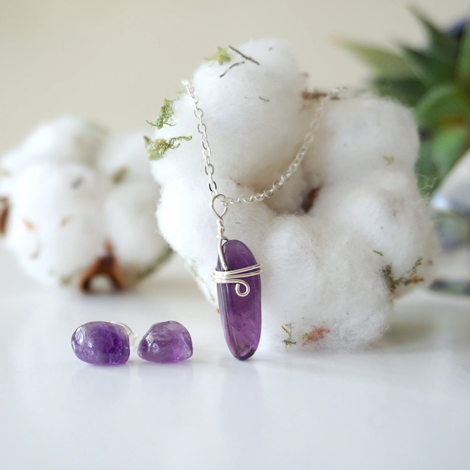 Front view of minimalist amethyst jewelry set with polished raw amethyst pendant necklace and amethyst stud earrings in silver setting
