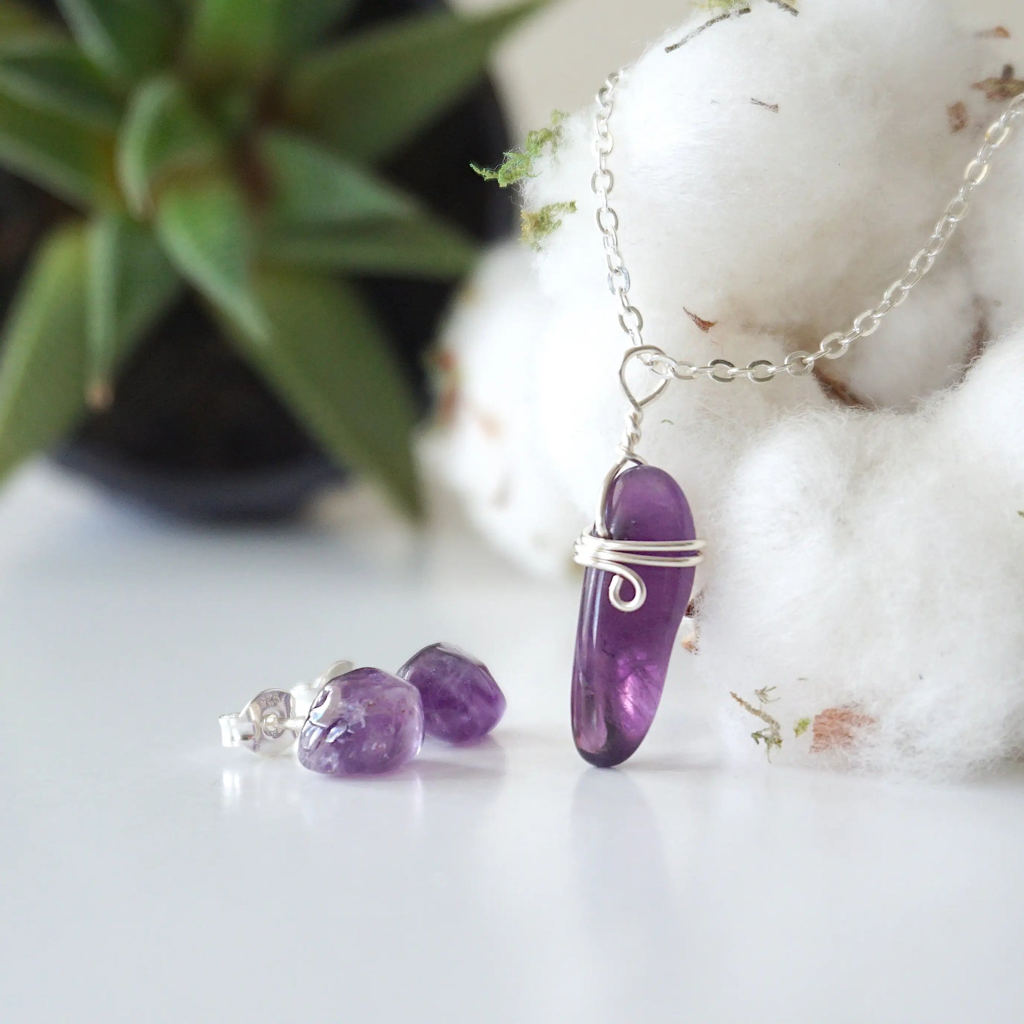 Side angle view of minimalist amethyst jewelry set showing polished raw amethyst pendant and amethyst stud earrings in silver