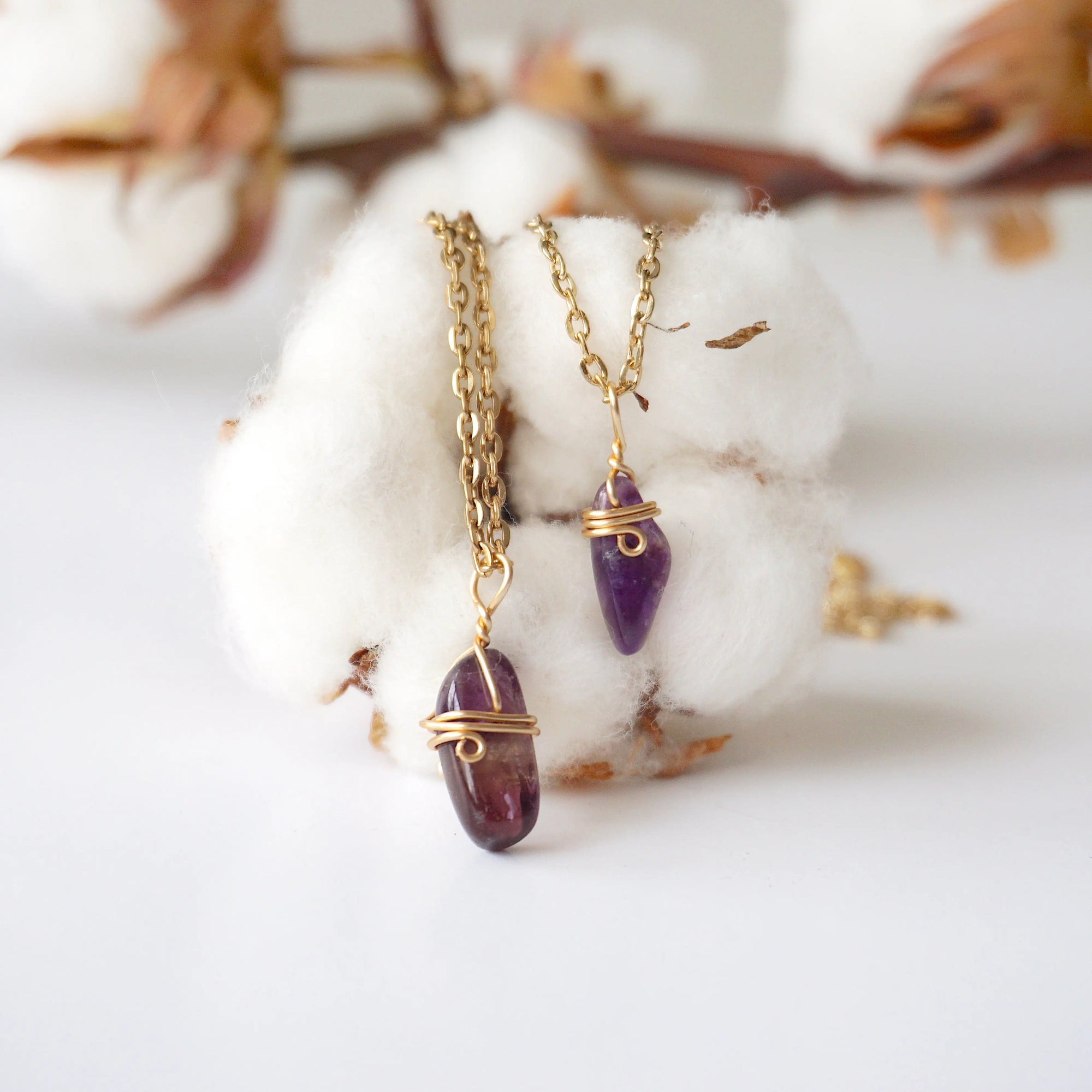 Two minimalist amethyst necklaces showing natural variation in raw amethyst pendant size, shape, and color, gold plated copper wire wrap