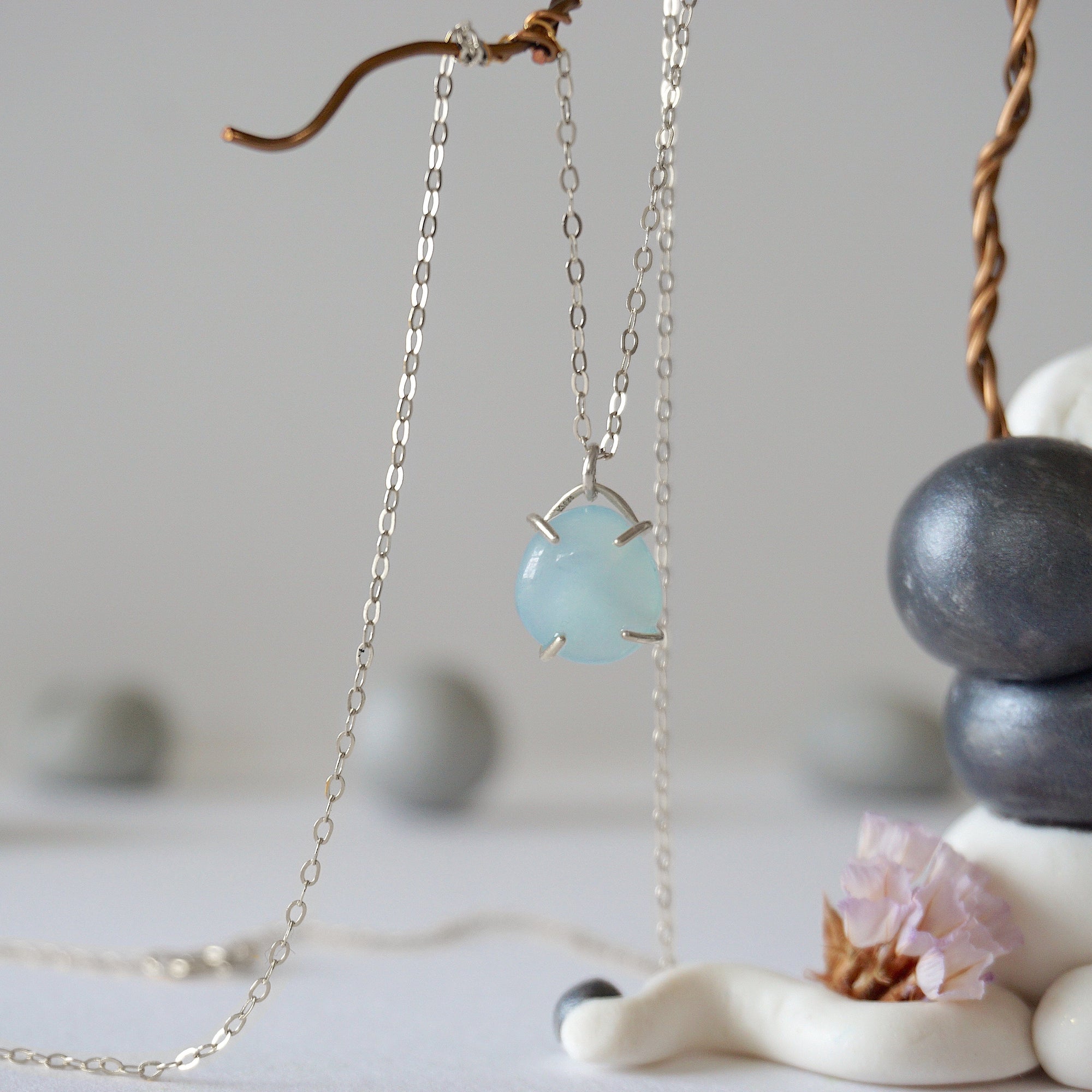 Minimalist aquamarine necklace hanging on display, detailed front view, genuine gemstone in 925 sterling silver claw setting, Designs by Nature Gems